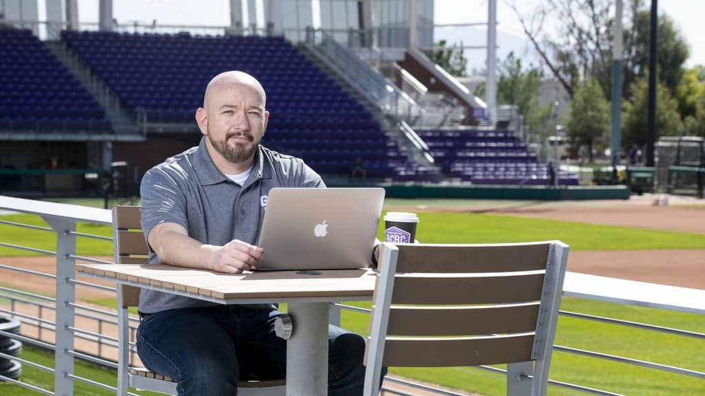 Man sitting outside at table with laptop