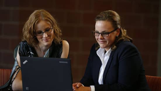 Two adult learners looking at laptop