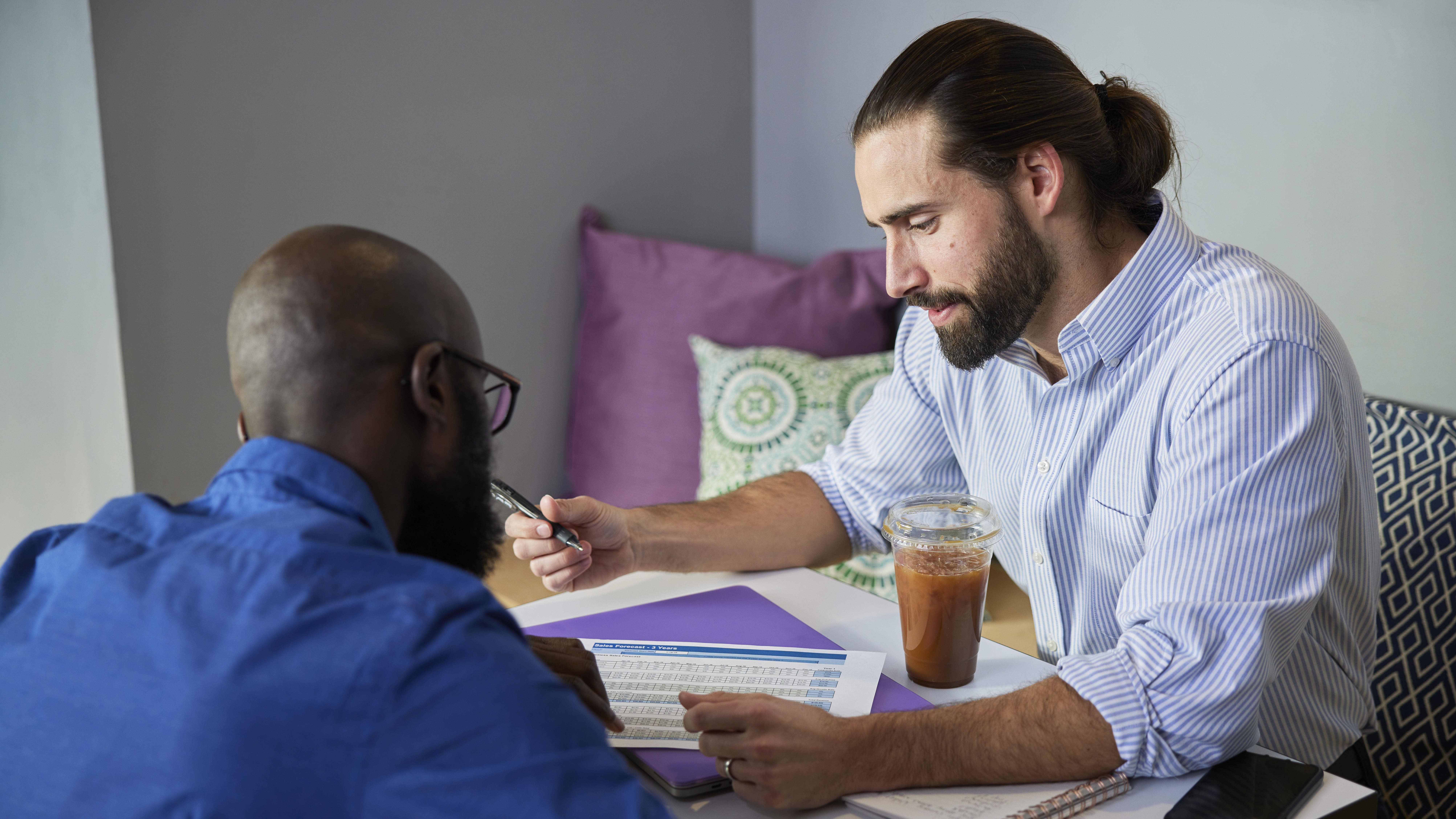 Two male professionals completing evening degree coursework in break room