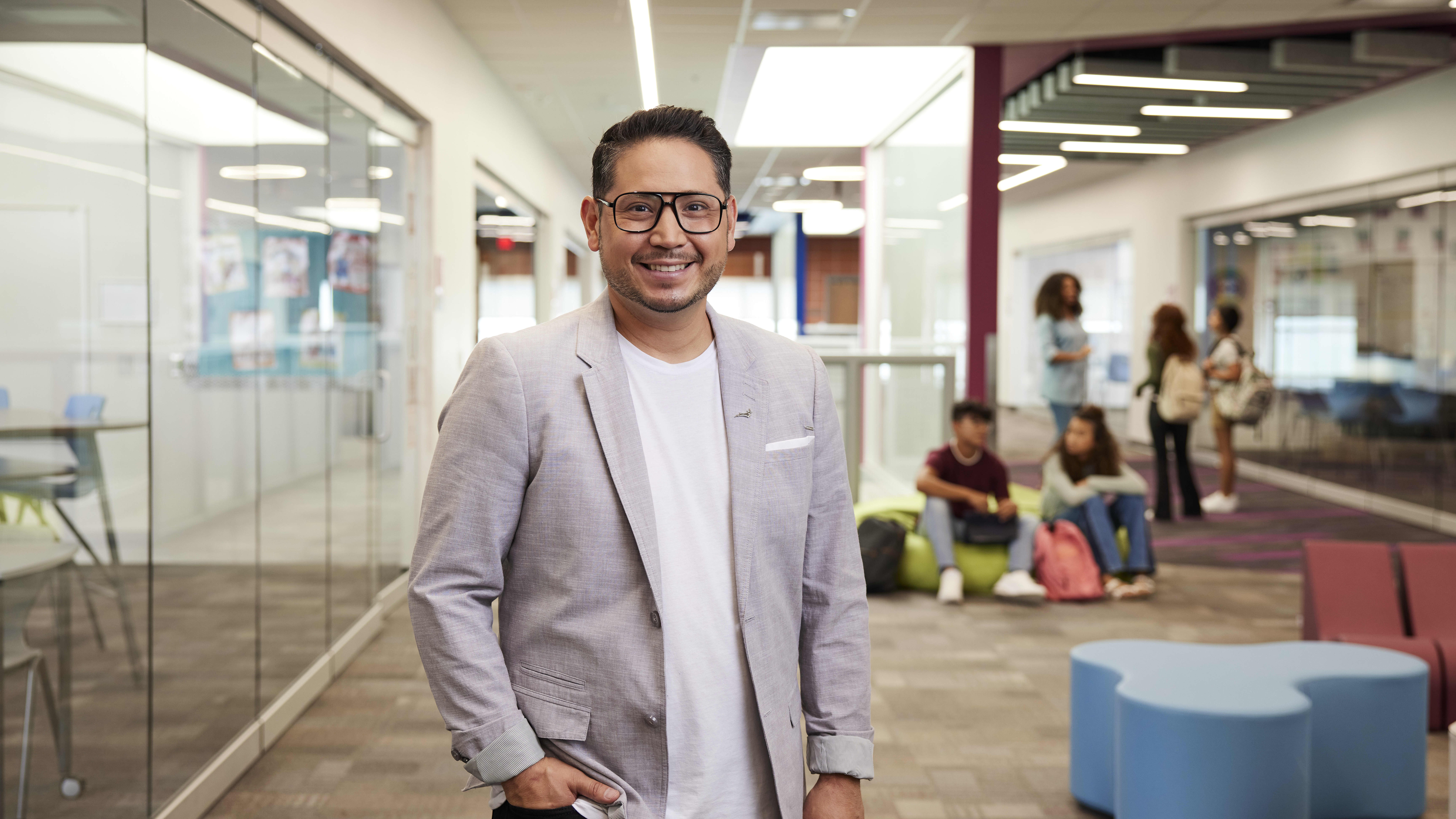 Teacher Stands in School Smiling at Camera After Earning MEd From GCU