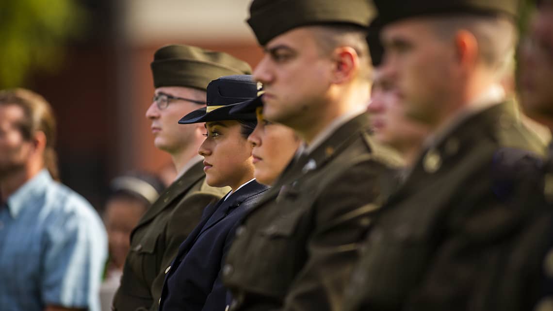 Group of ROTC cadets sit in swearing in outfits at the ROTC Commissioning Ceremony