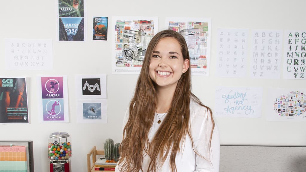 BA in Advertising and Graphic Design Student Smiles in Front of GCU Portfolio