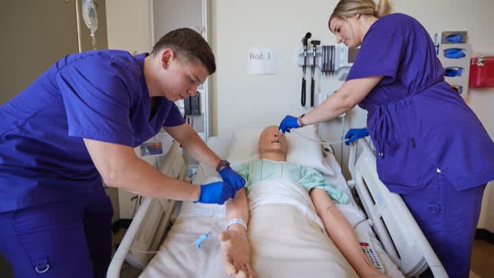 Male and female nursing degree students completing GCU lab in hospital