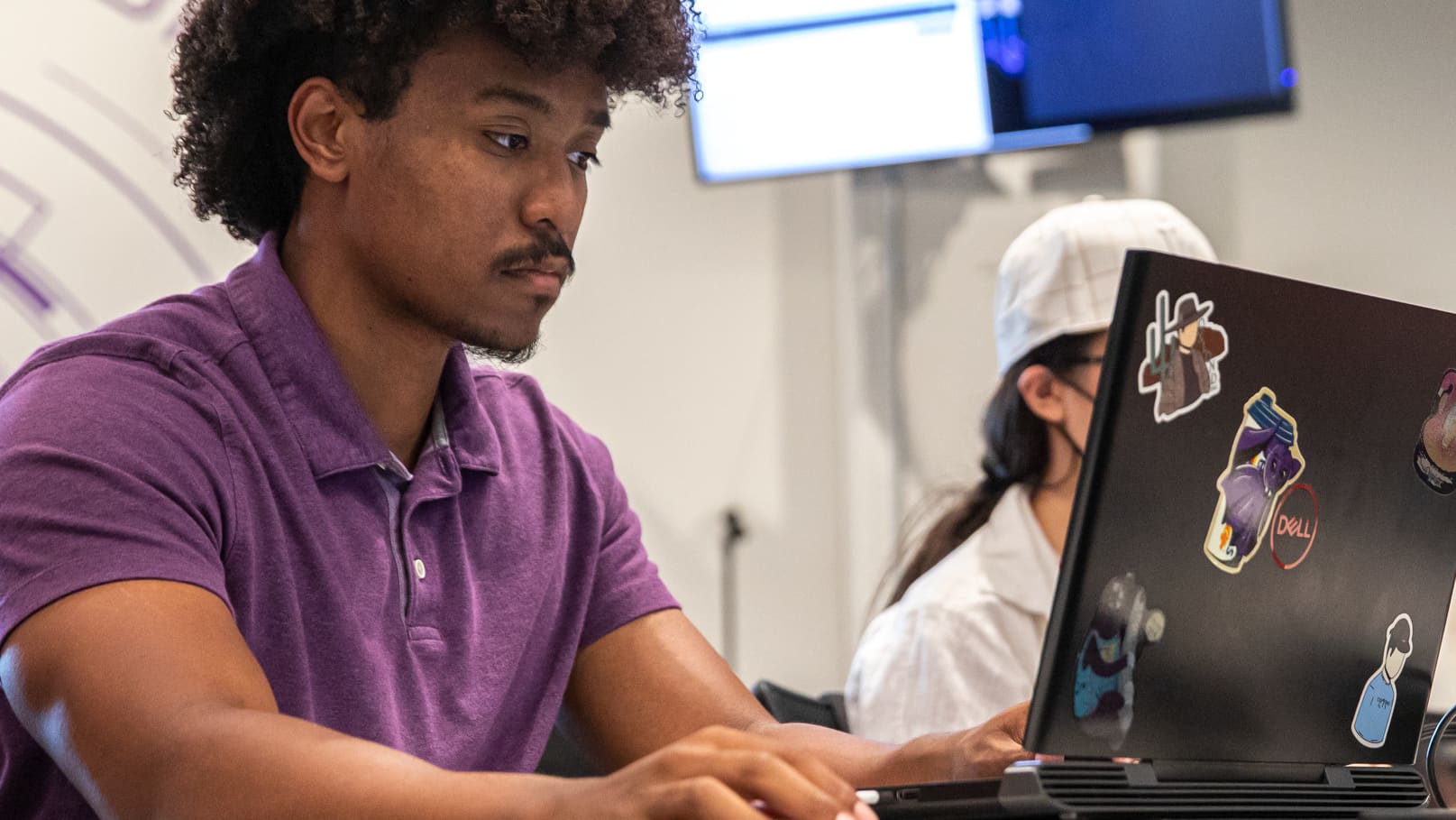 Software development student sitting at a table with a laptop while working on code