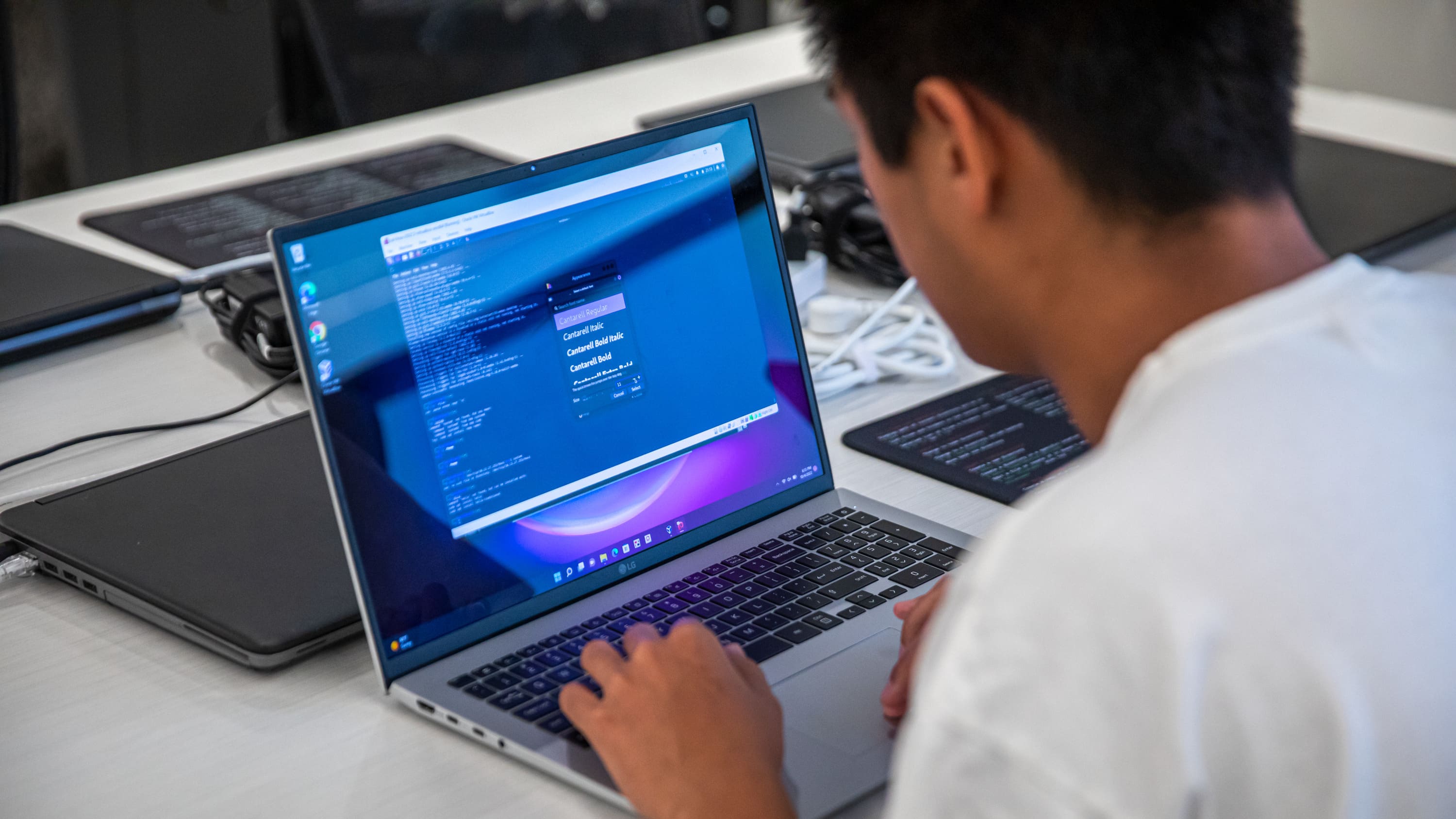 Programming student sitting at a desk with a laptop with coding applications on the screen
