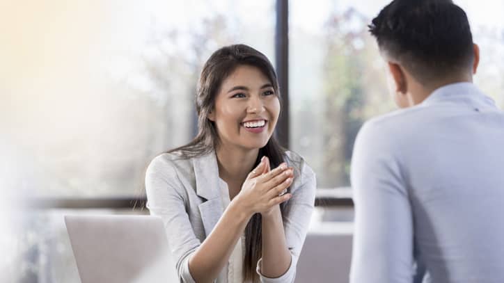 Woman sitting in front of man discussing healthcare and smiling