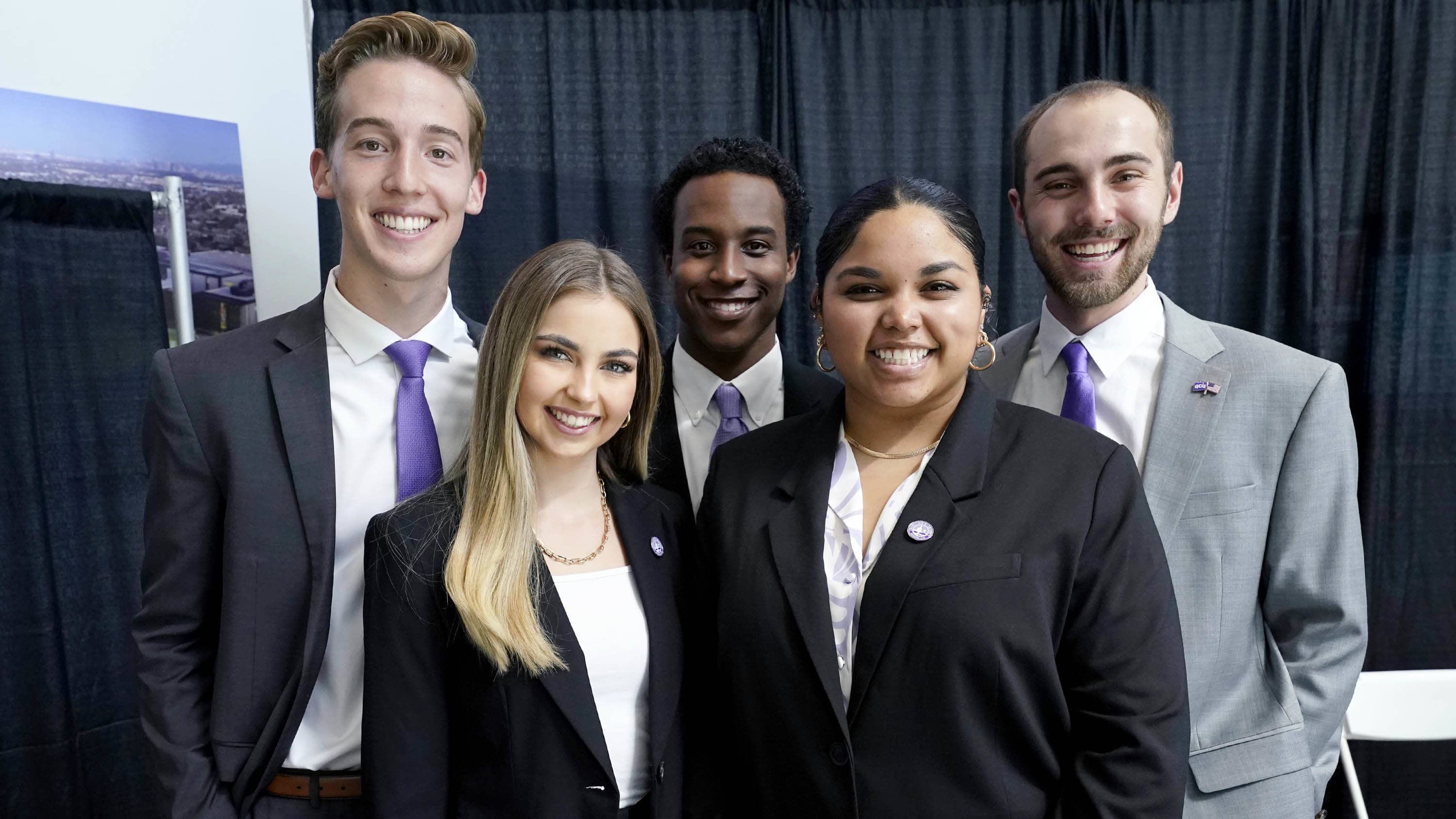 Diverse group of students in business attire smiling for a photo