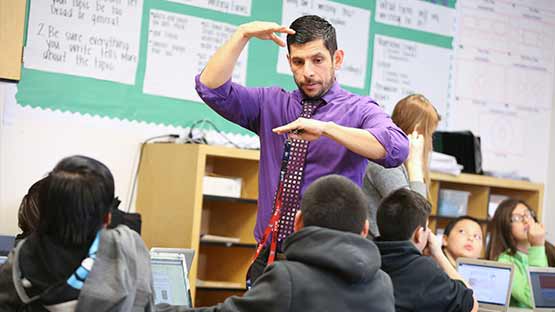 Male teacher in classroom giving lecture to elementary-aged class