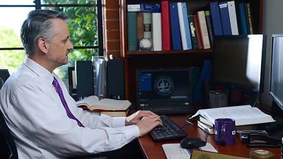 professor typing at computer in office