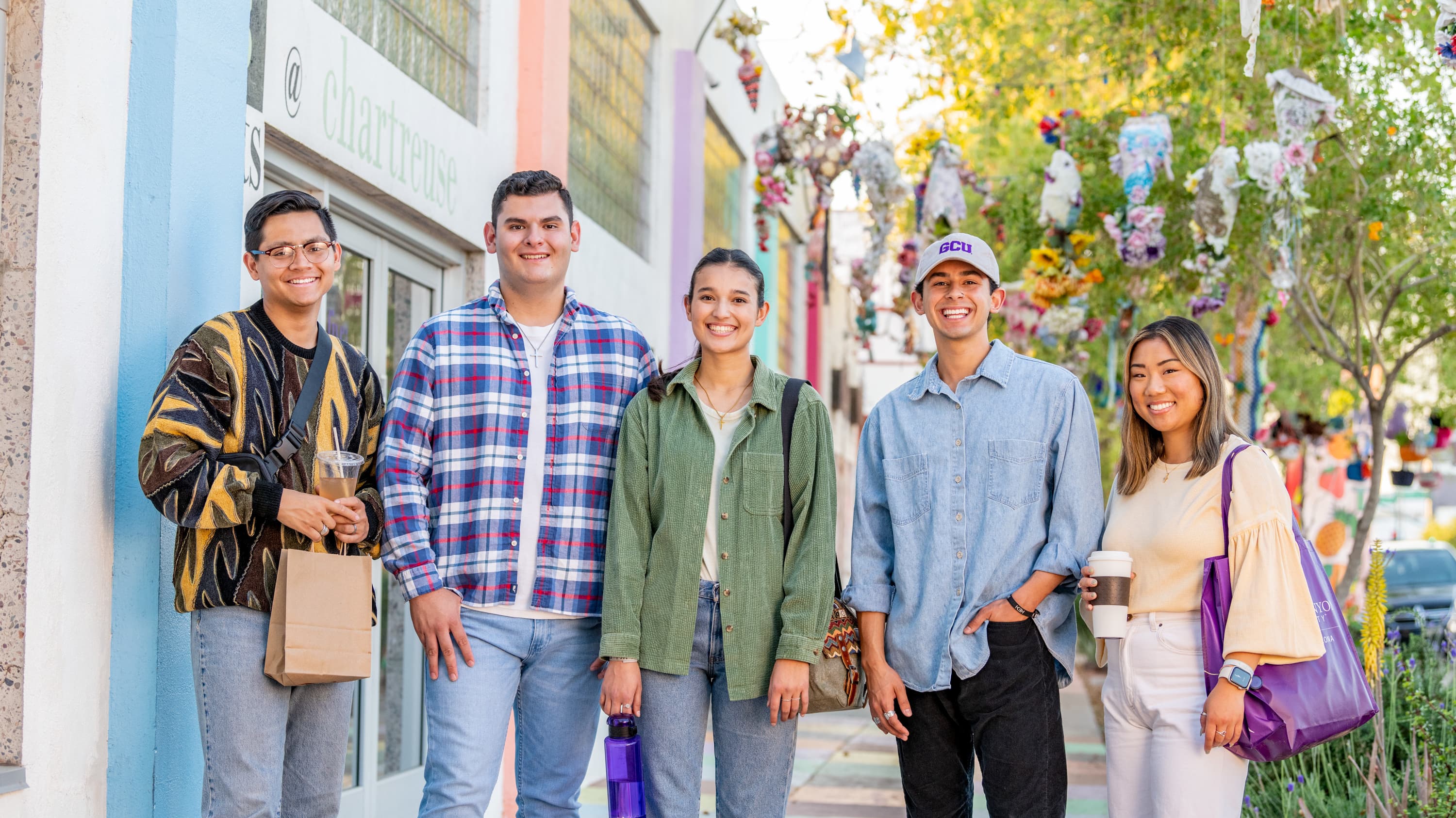 A diverse group of students standing together outside of campus smiling at camera