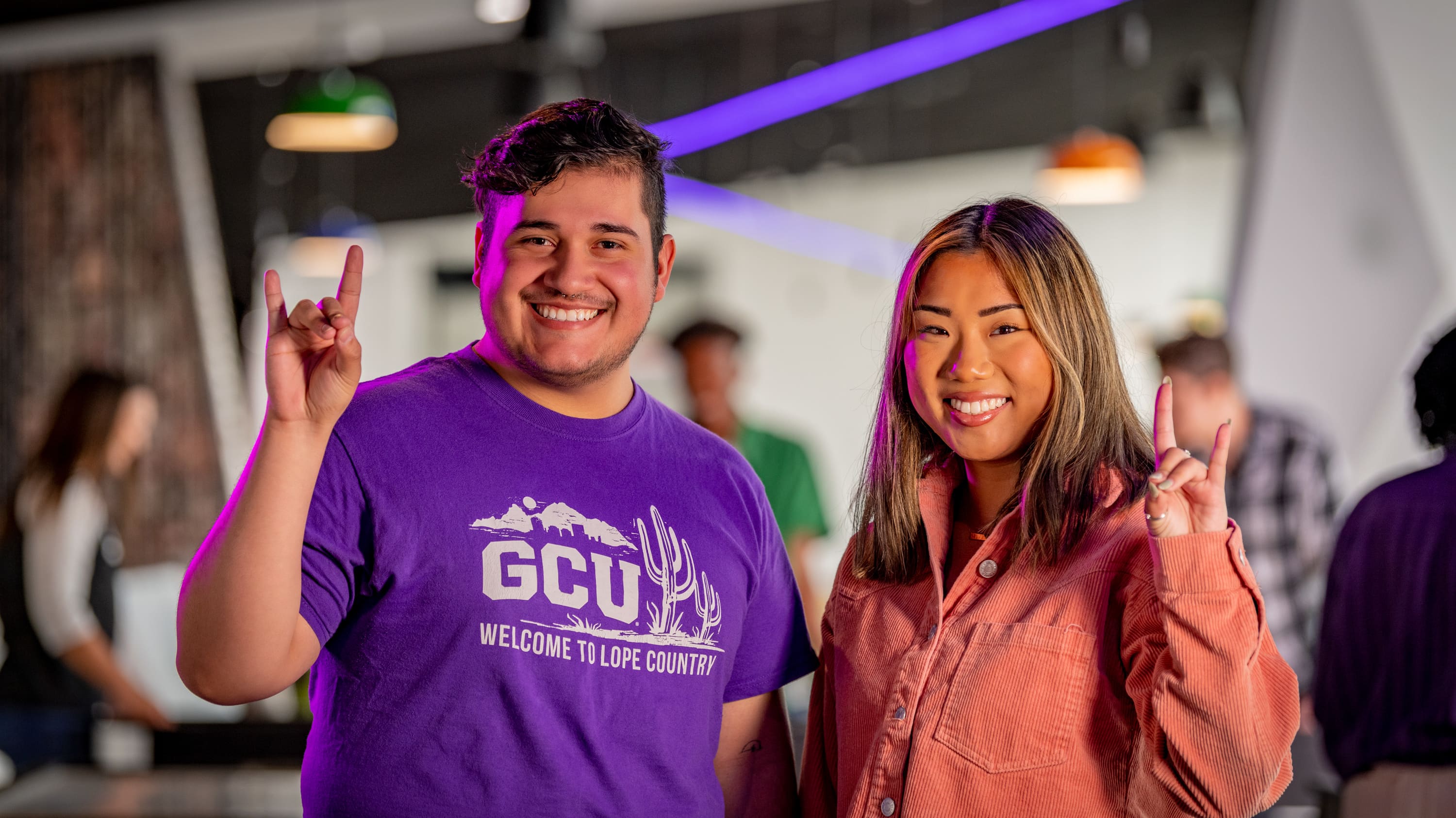 Male and female bachelor's student holding Lopes Up hand sign at GCU's campus