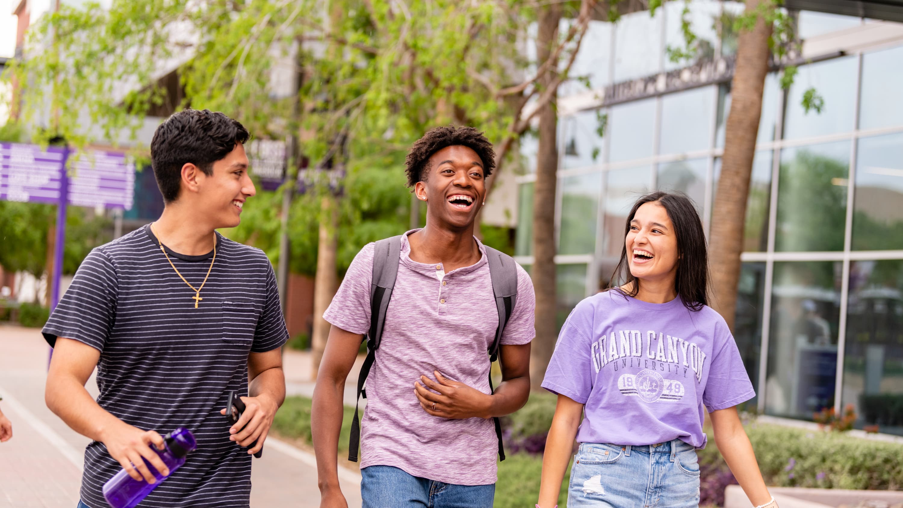 Male and female students laughing and walking outside on GCU's campus