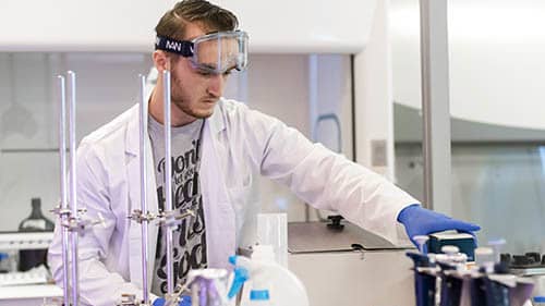 Chemistry student in white lab coat in chemistry lab