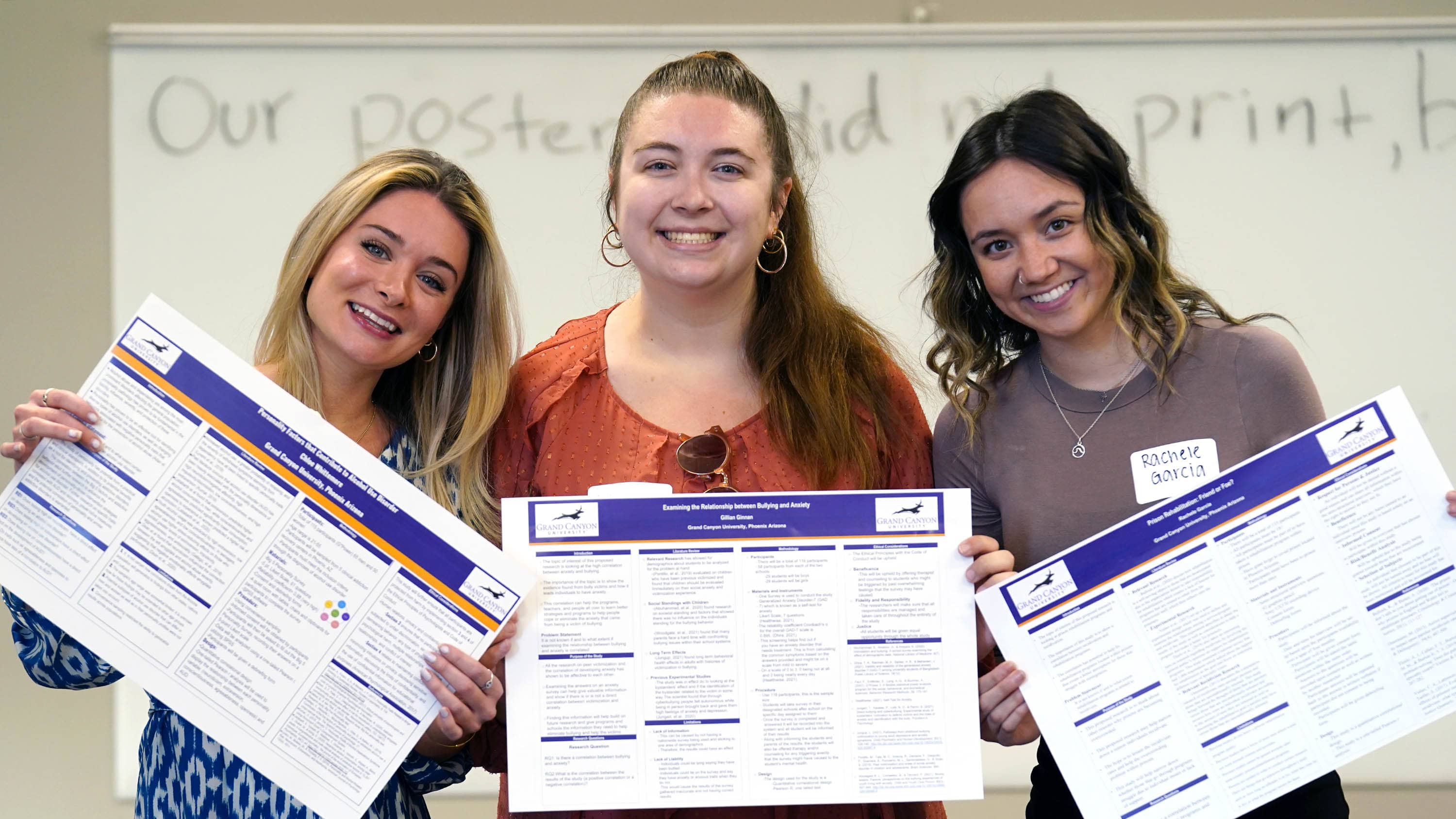 Three female criminal justice degree students smiling with report at GCU senior showcase event