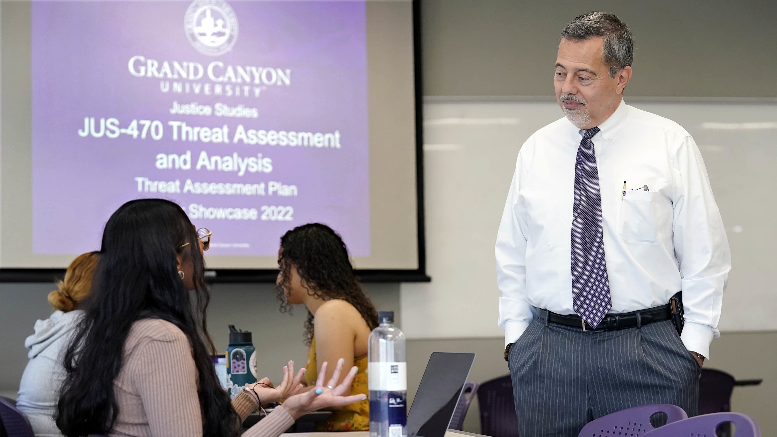 Bachelor's justice studies degree students talking with professor in classroom