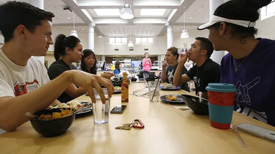 Students sitting at a table eating lunch in cafeteria