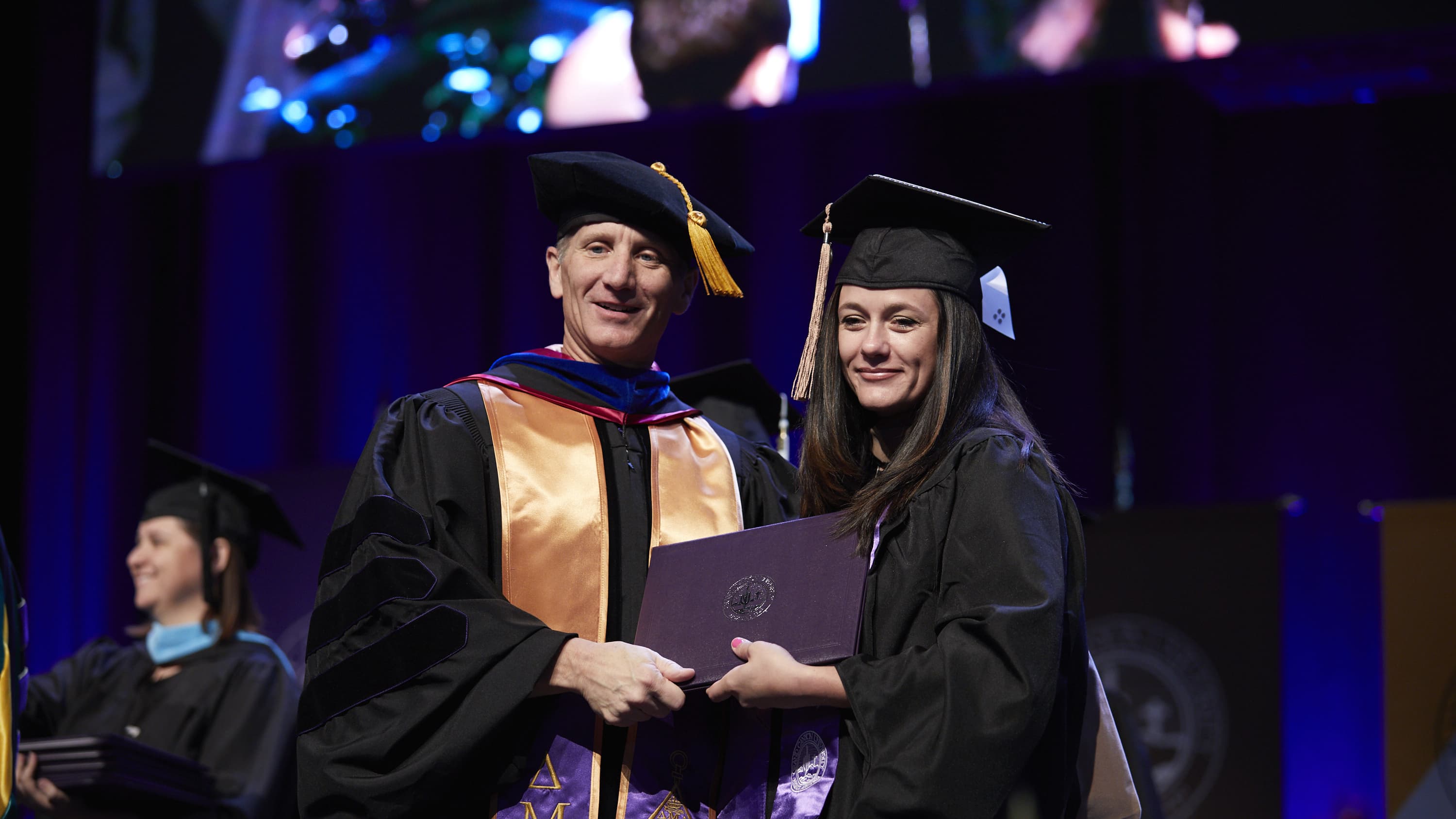 Dr. Gibb shaking hands with student at commencement ceremony