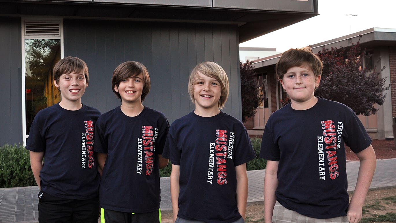 Four male students in matching shirts smiling