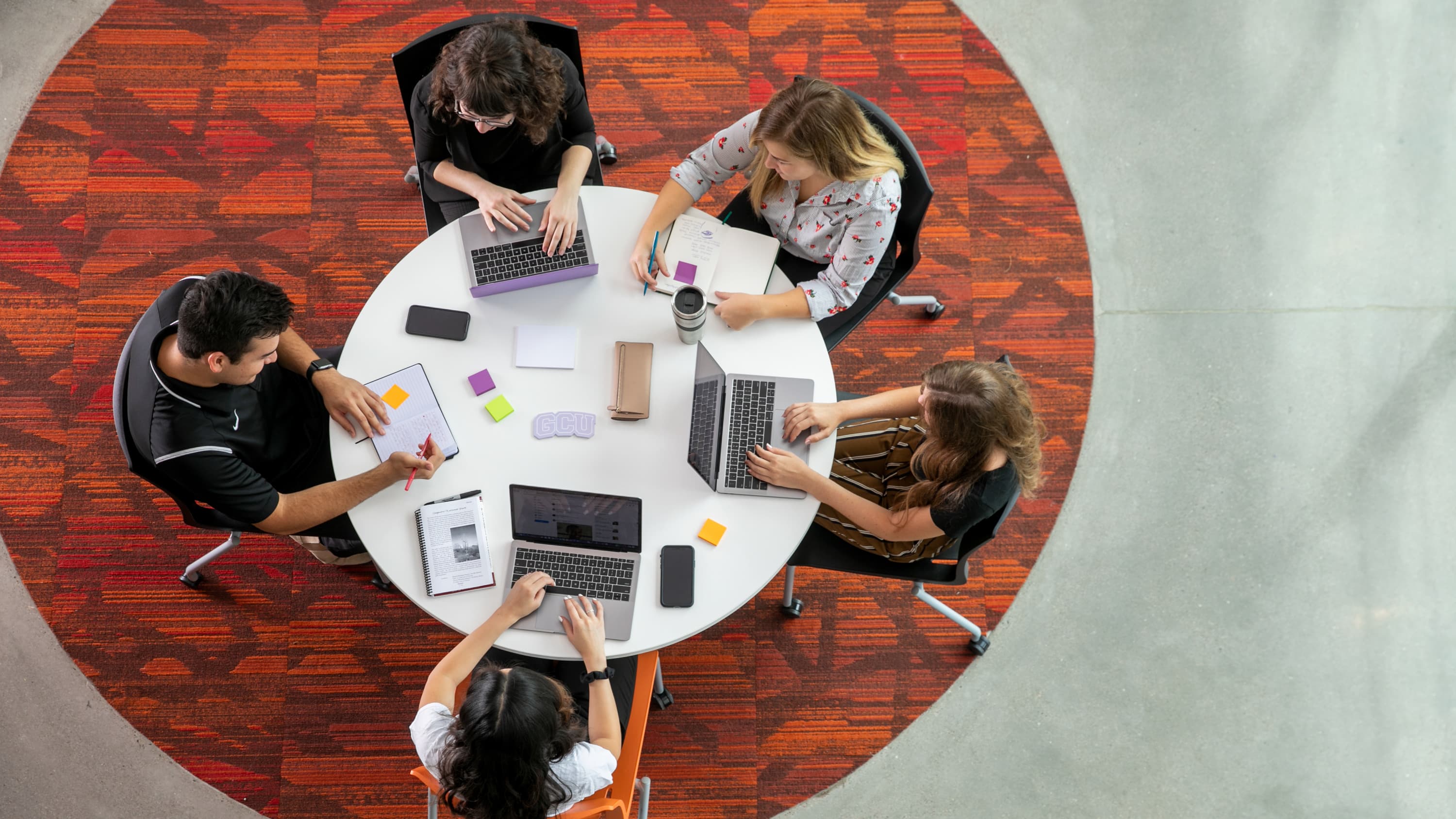 Students gathered at a table on their computers