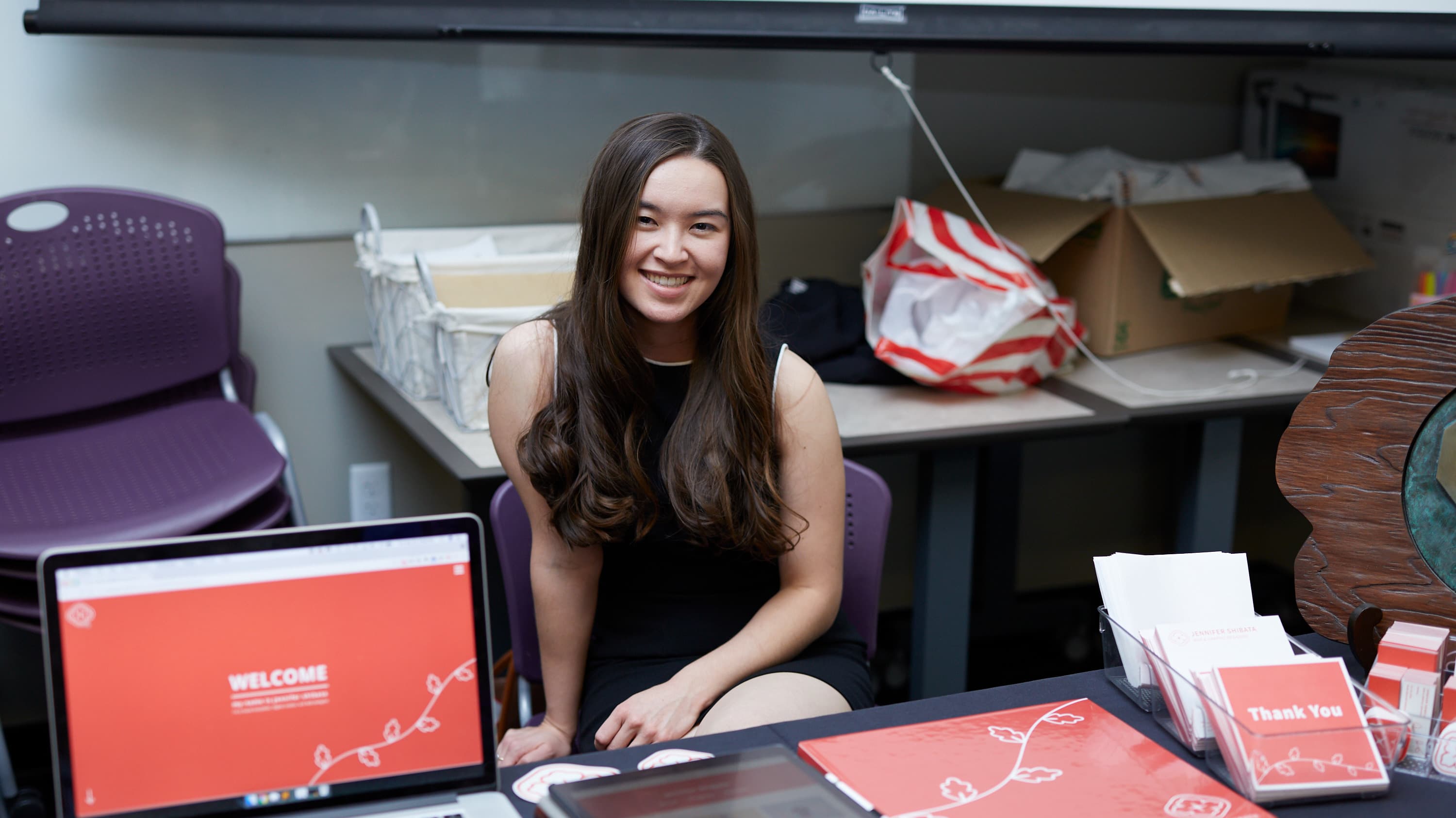 Female digital arts degree student smiling at GCU with portfolio and laptop