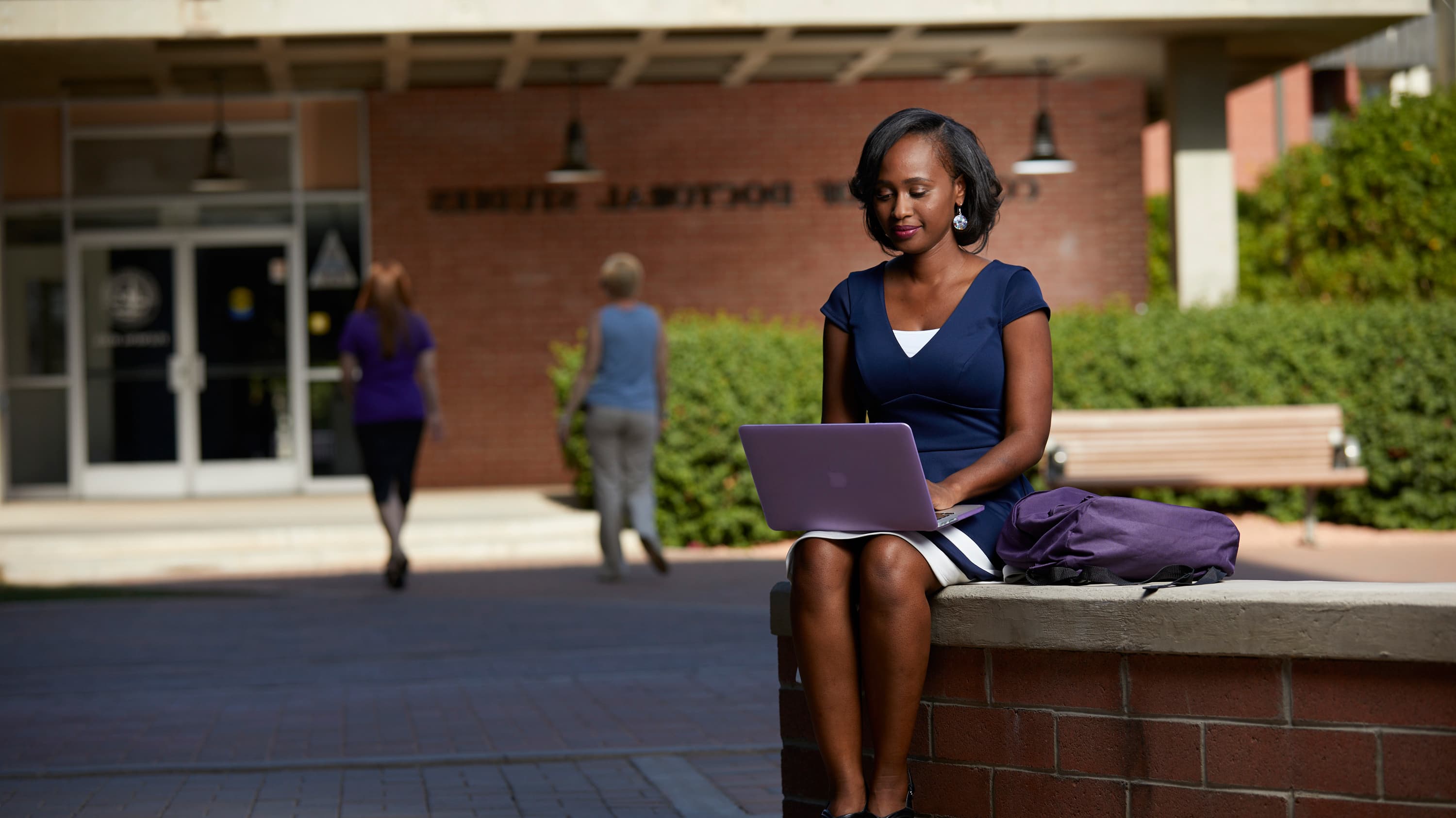 Female criminal justice certificate student working on laptop outside at GCU