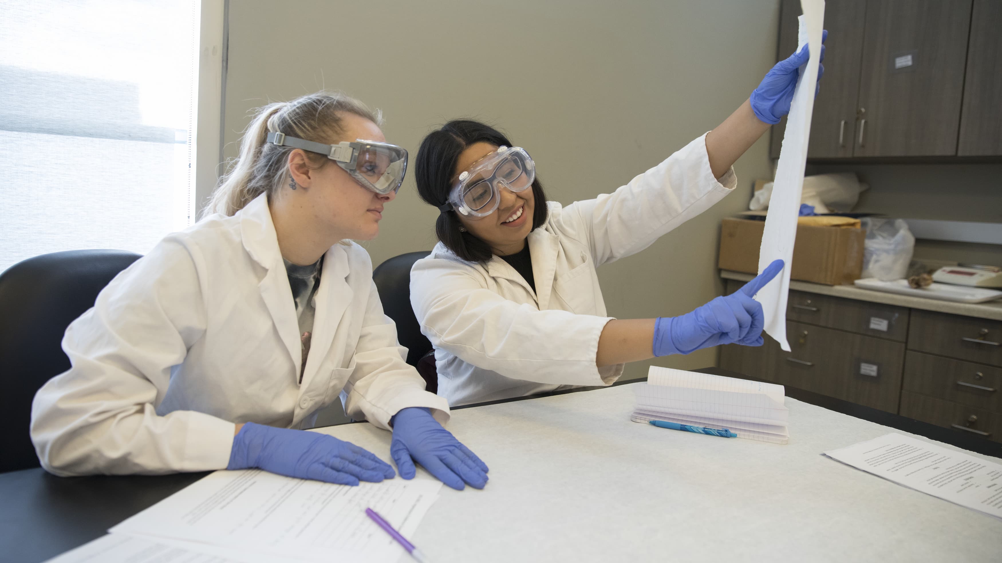 Two female forensic science degree students in GCU lab reviewing report