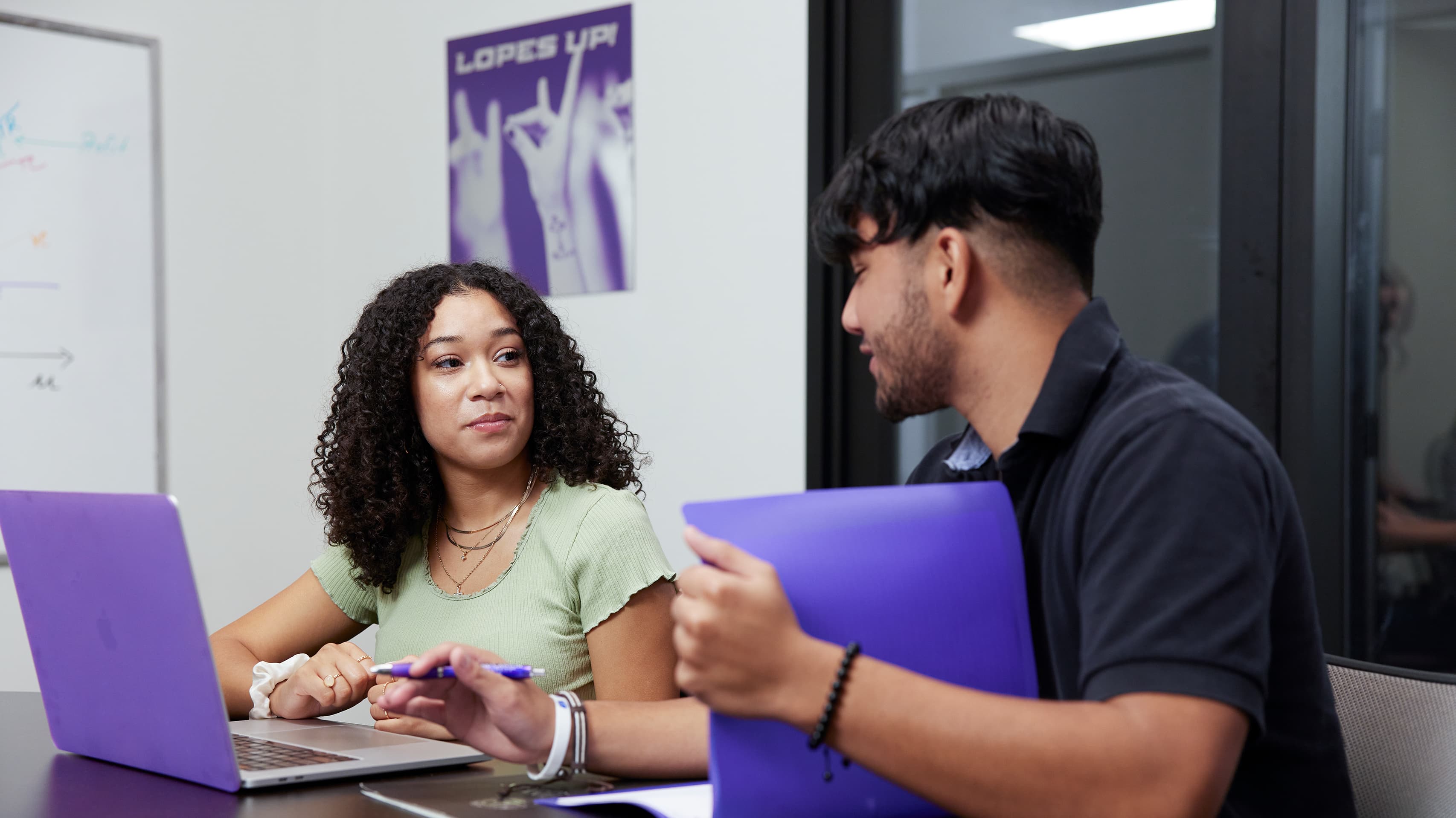 Students speaking at a table with laptop