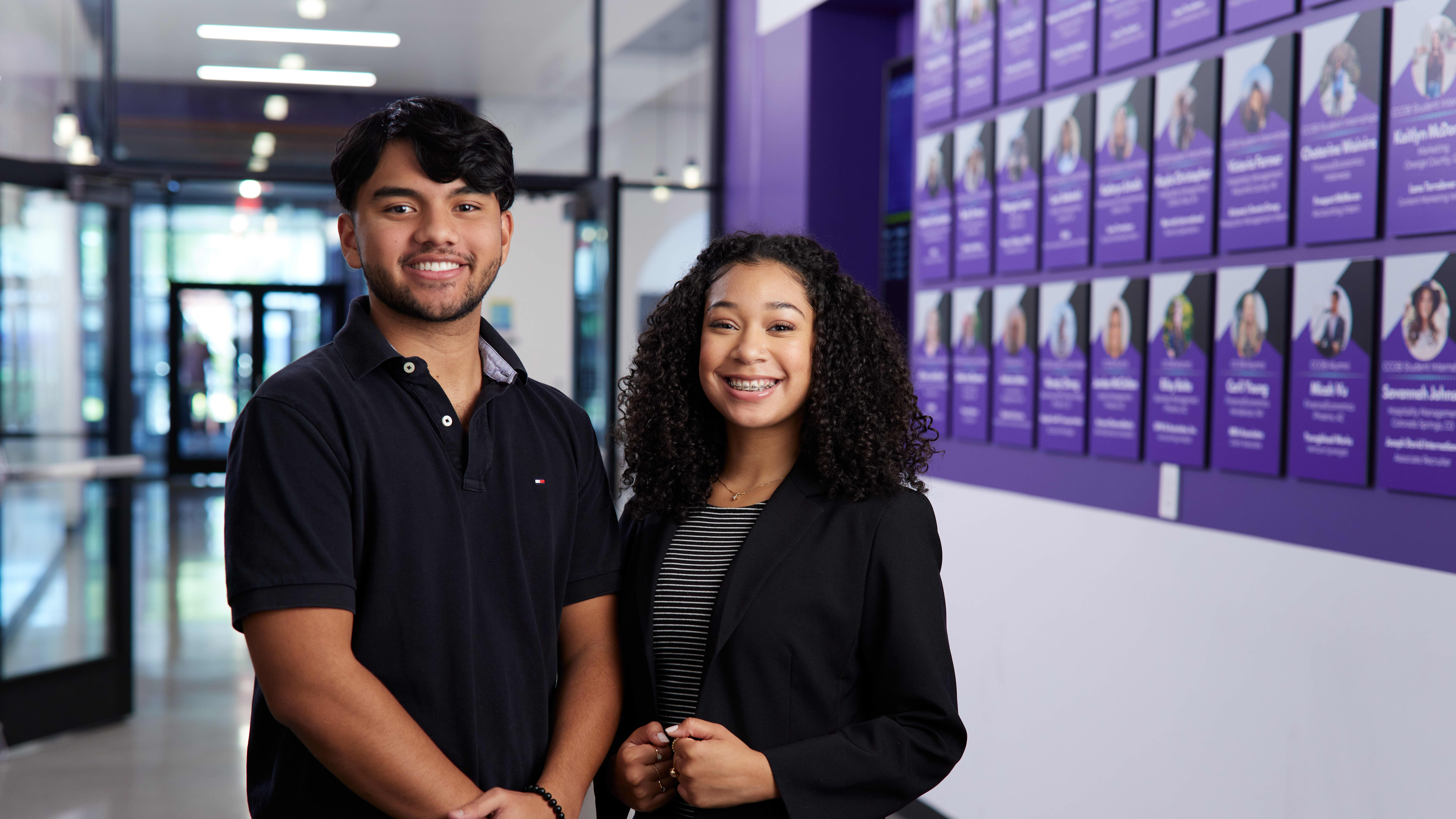 Male and female business master's degree students smiling in GCU hallway
