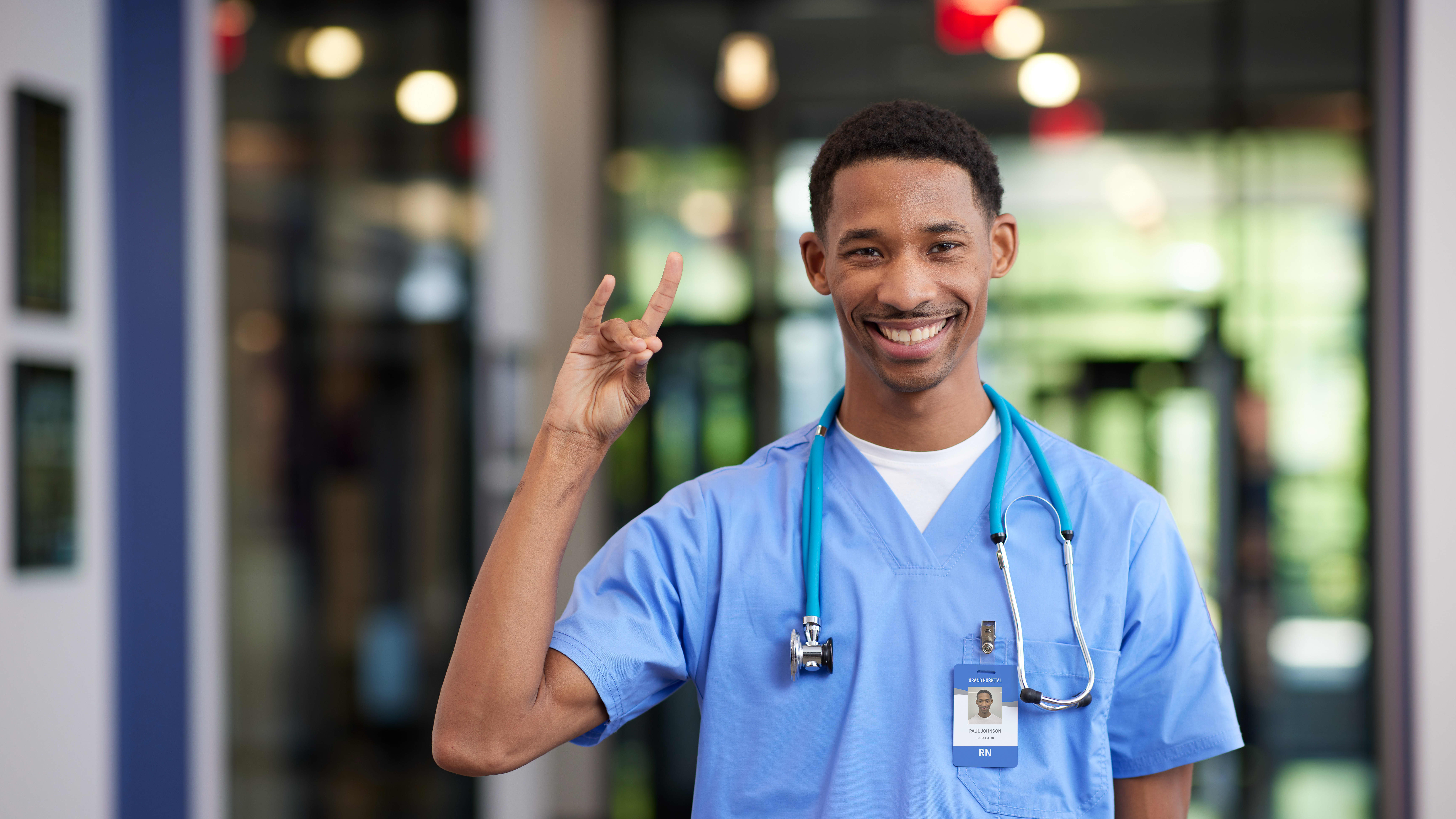 Male MSN degree student smiling with Lopes Up hand sign in hospital at GCU