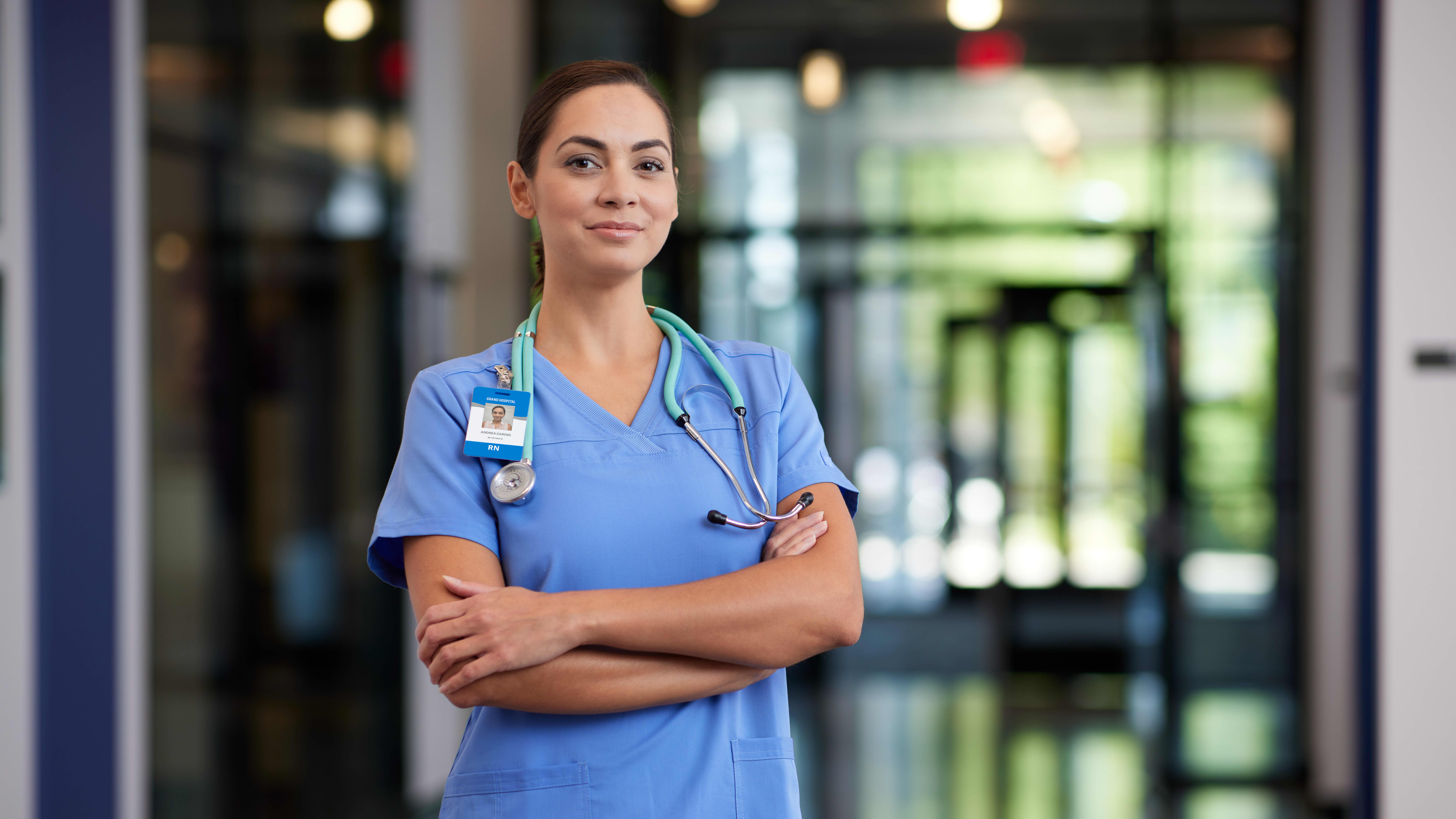 Portrait of female MSN degree graduate wearing blue scrubs in hospital hallway