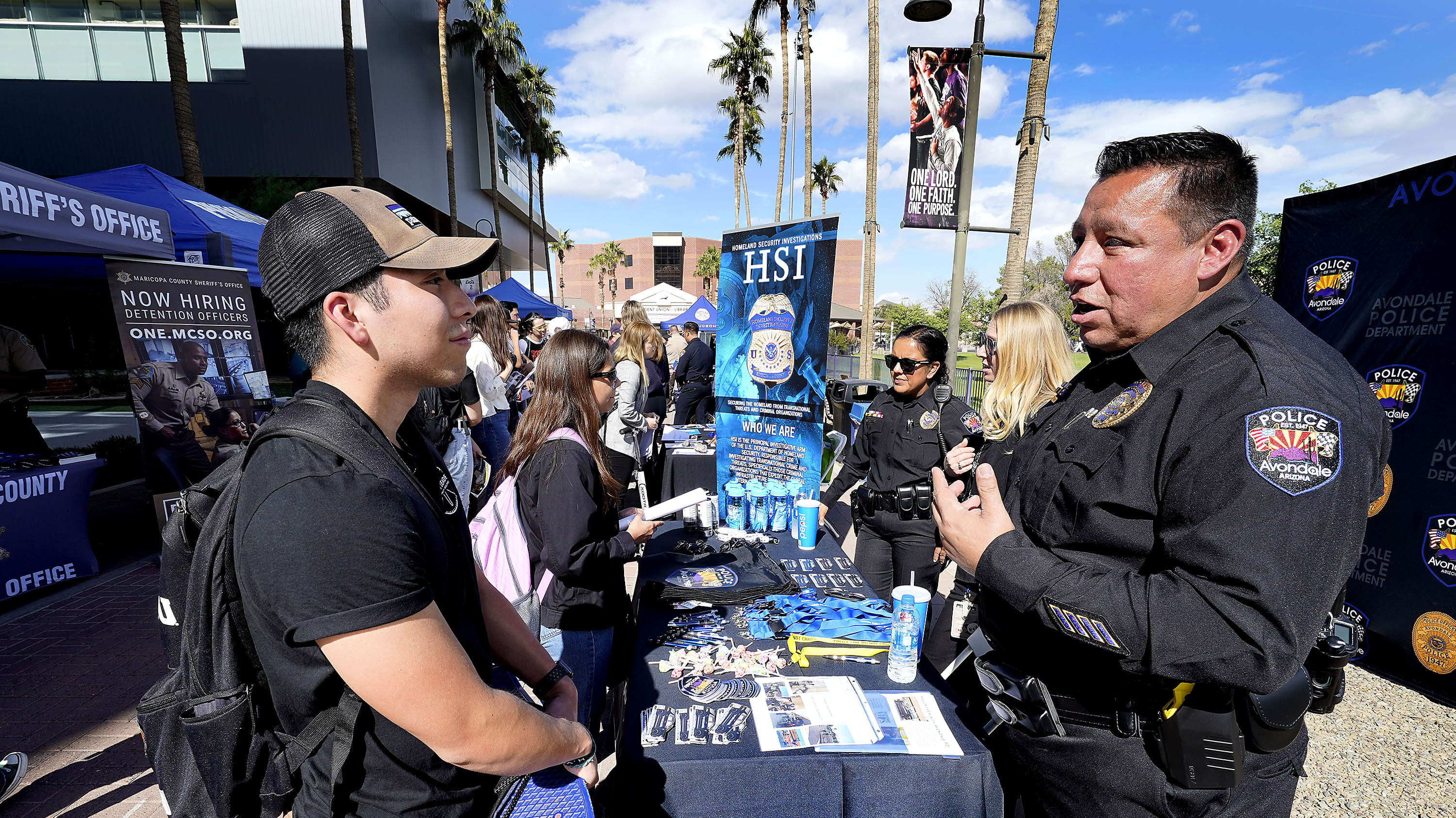 Male legal studies student talking with police officer at GCU career fair