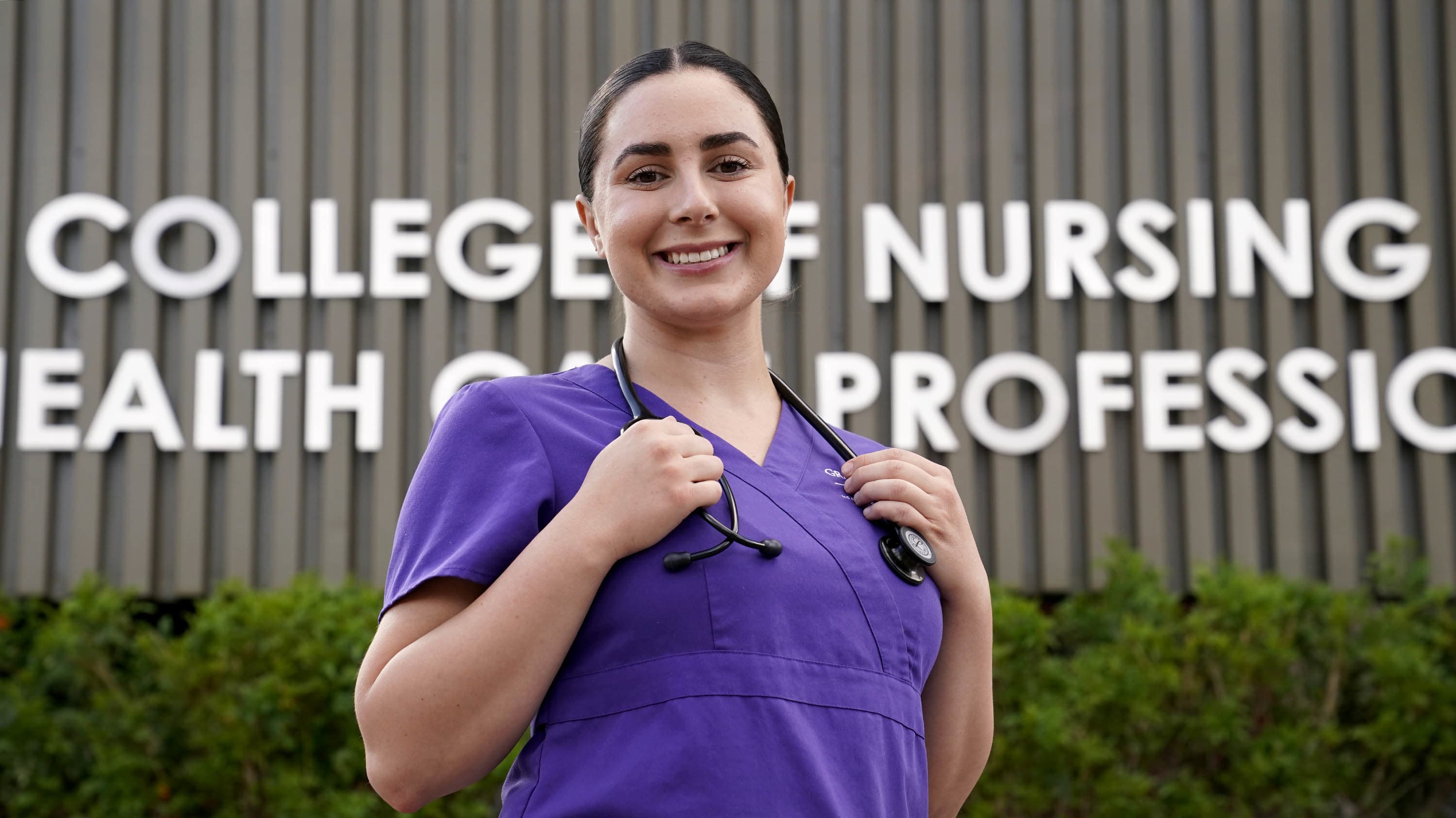 Female ABSN prereqs student smiling in front of GCU's College of Nursing building