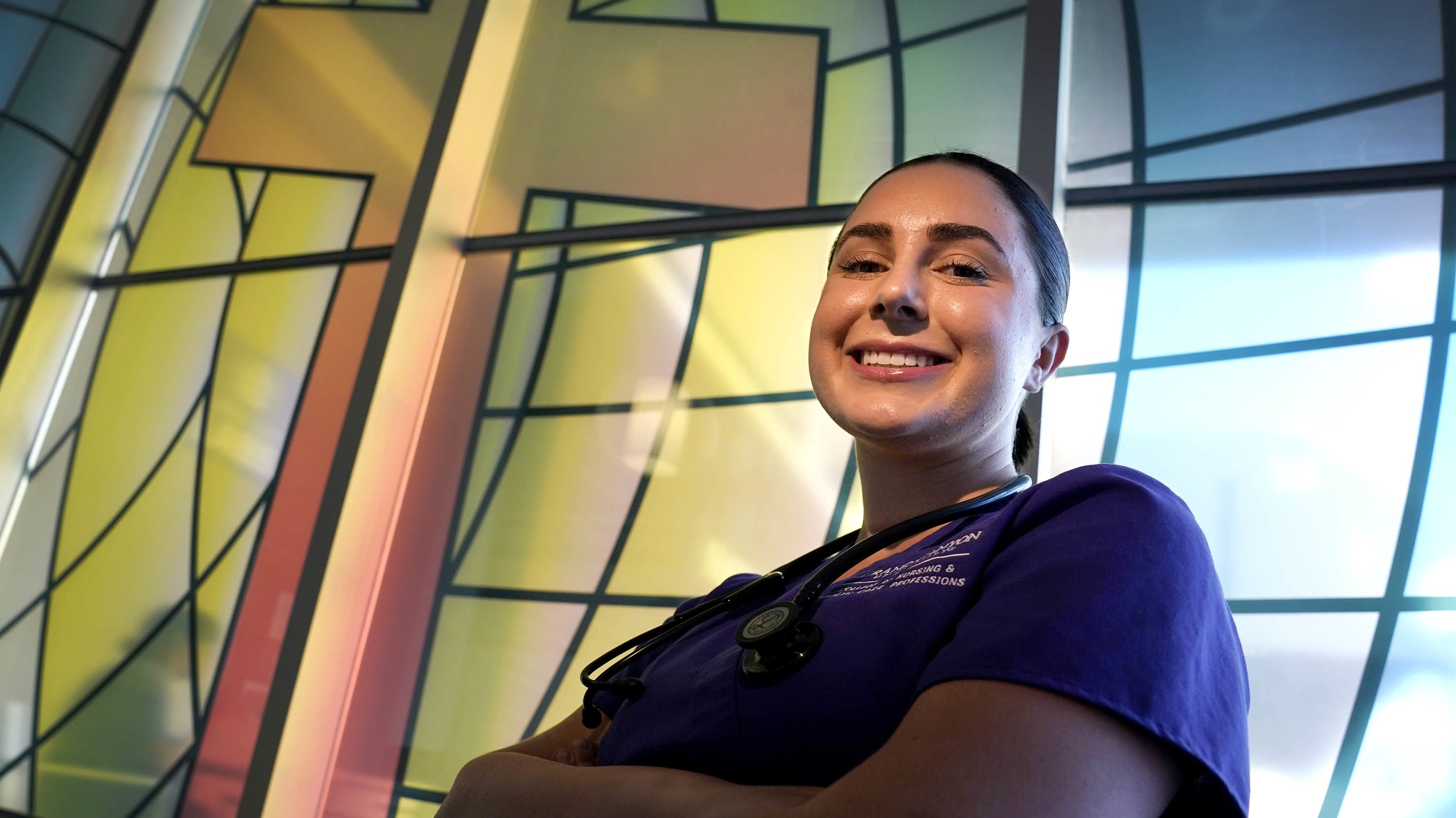 Female nursing degree student smiling in front of stained-glass window at GCU