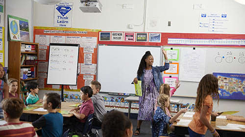 African american female teacher with long braids calls class to attention with fractions on board