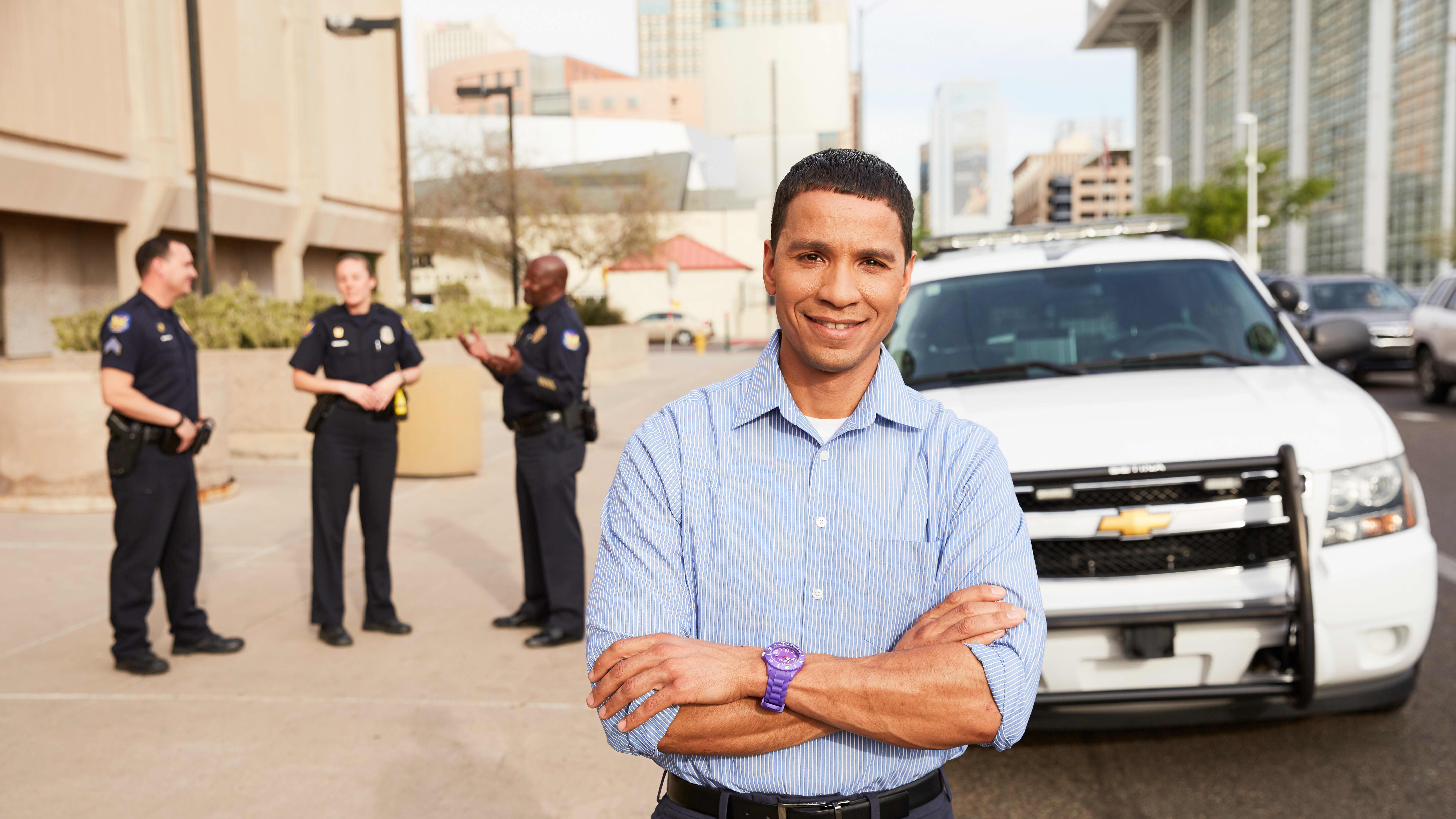Legal studies degree graduate smiling outside with police officers and car in background