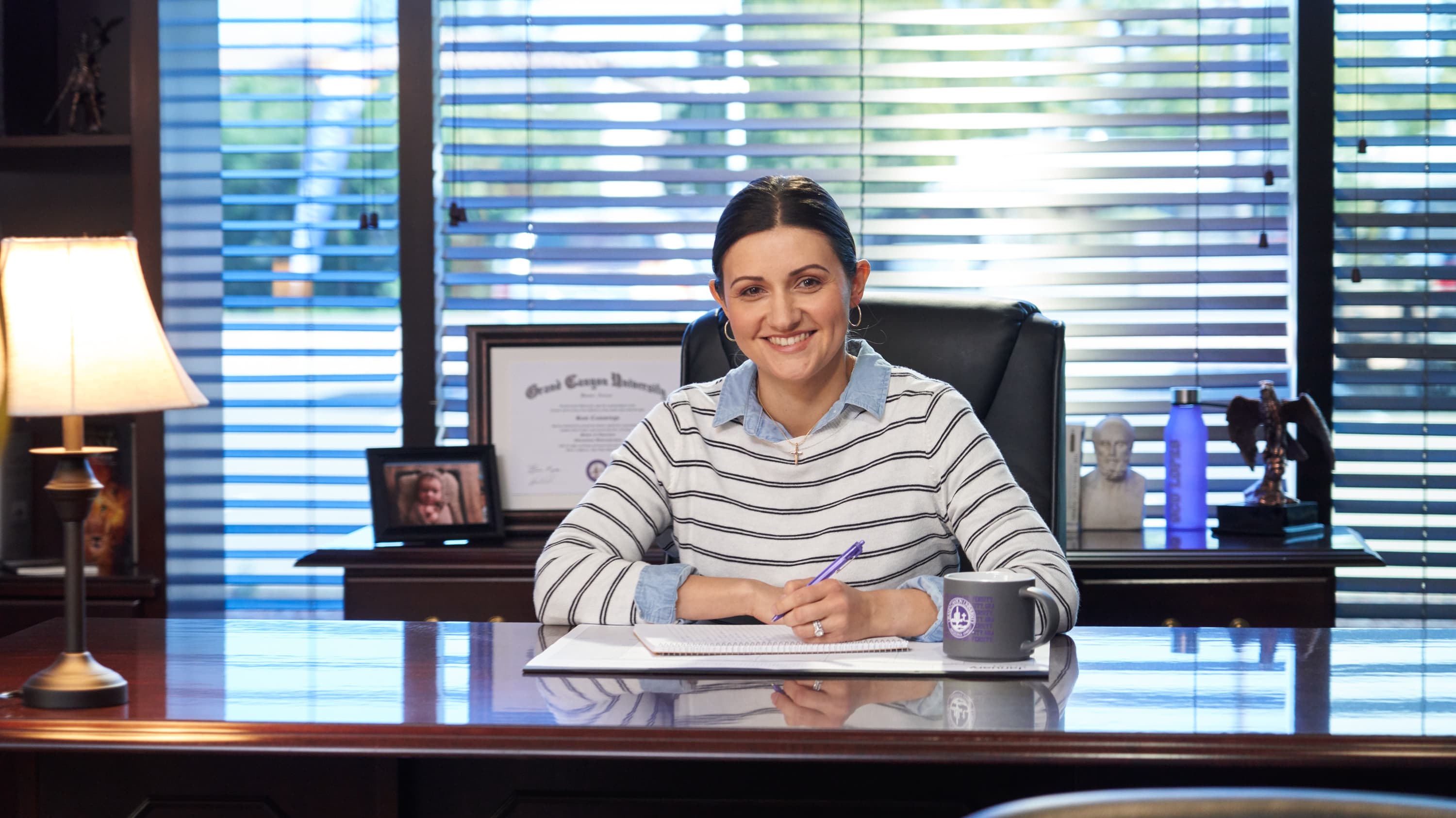 Female administration employee smiling at desk in her office at GCU