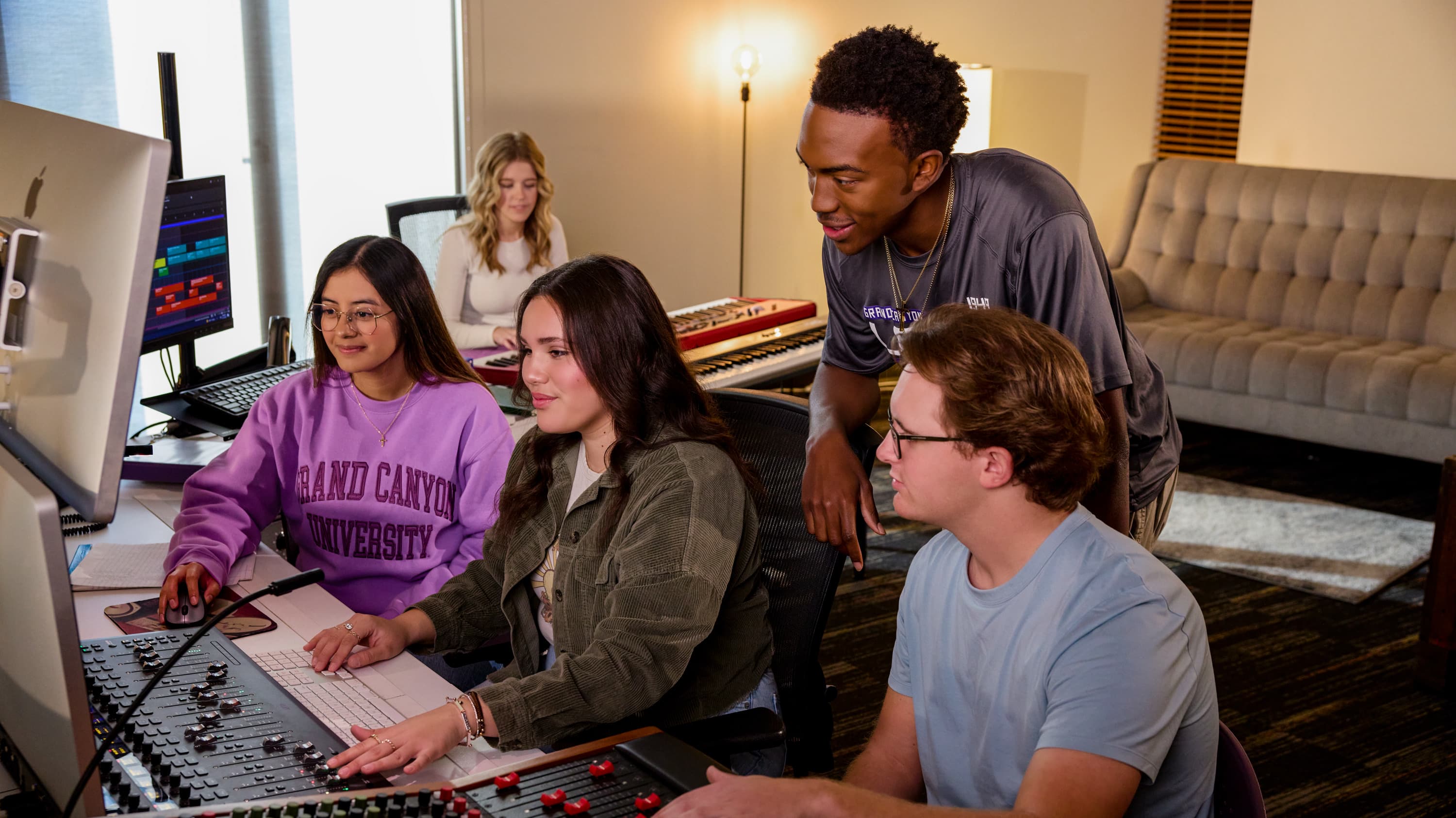 students in the recording studio working on the sound board