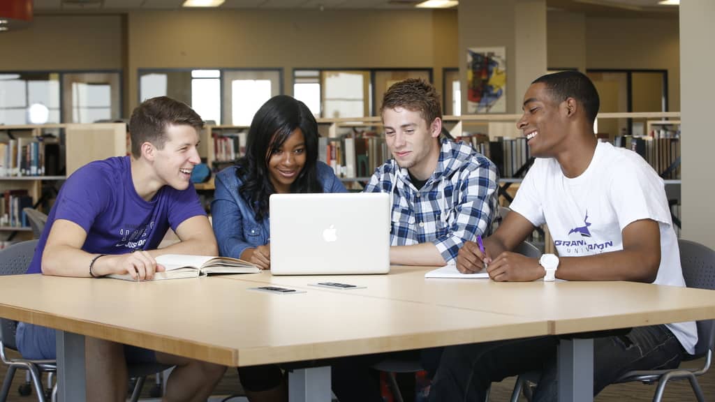 Group of GCU campus students review latest tuition fees on a laptop