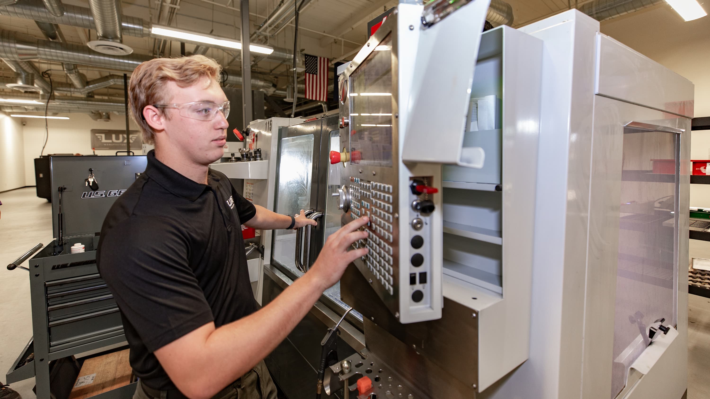 Caucasian male with blonde hair and a black shirt in CNC machinist lab