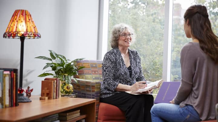 Female geropsychology degree graduate meeting with female client in office