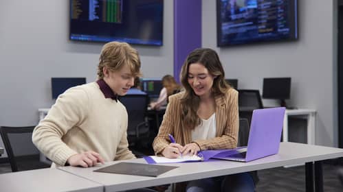 Business student working with classmate on computer