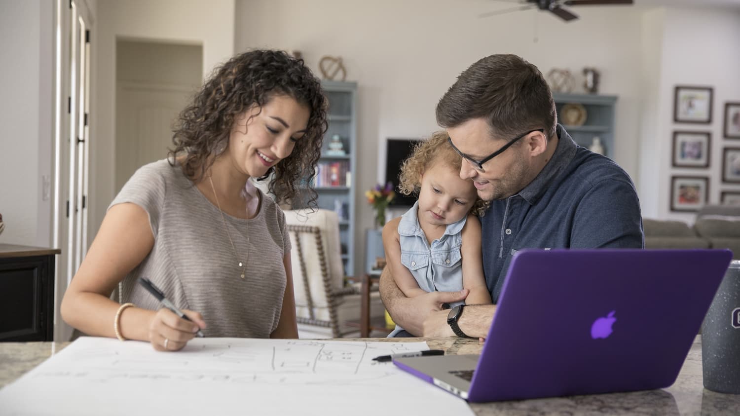 a husband and wife doing homework with their daughter