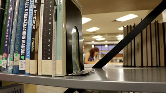 Student behind stack of books in library