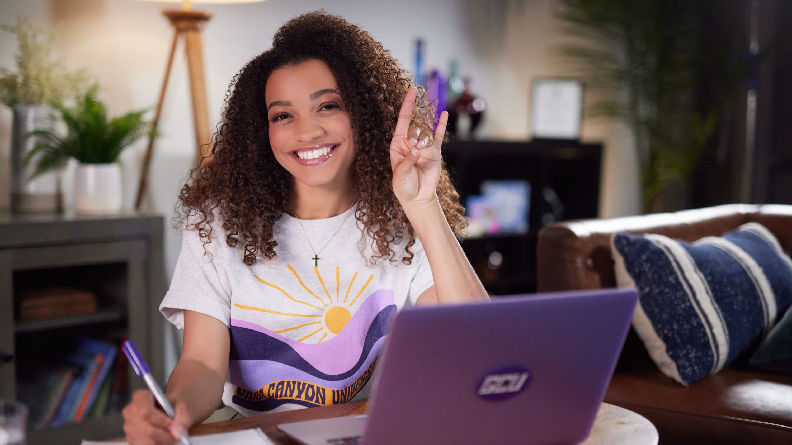 Student studying at computer holding lopes up sign 