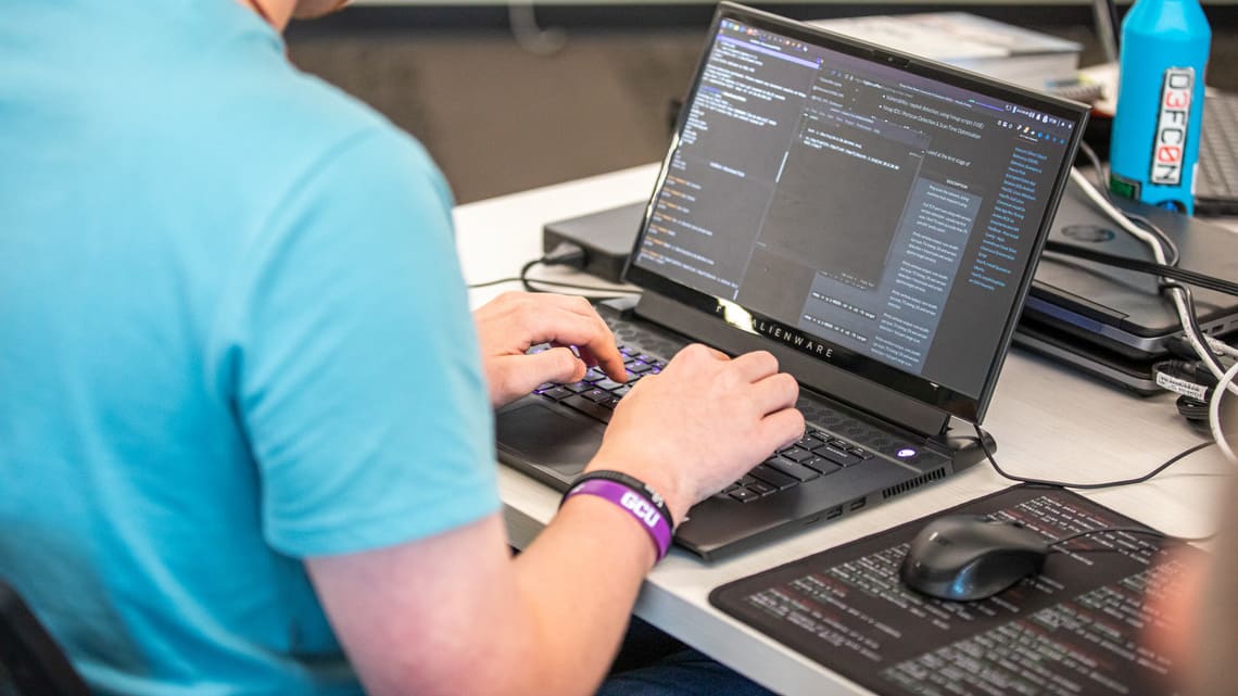 Software development student typing on a computer in a lab setting