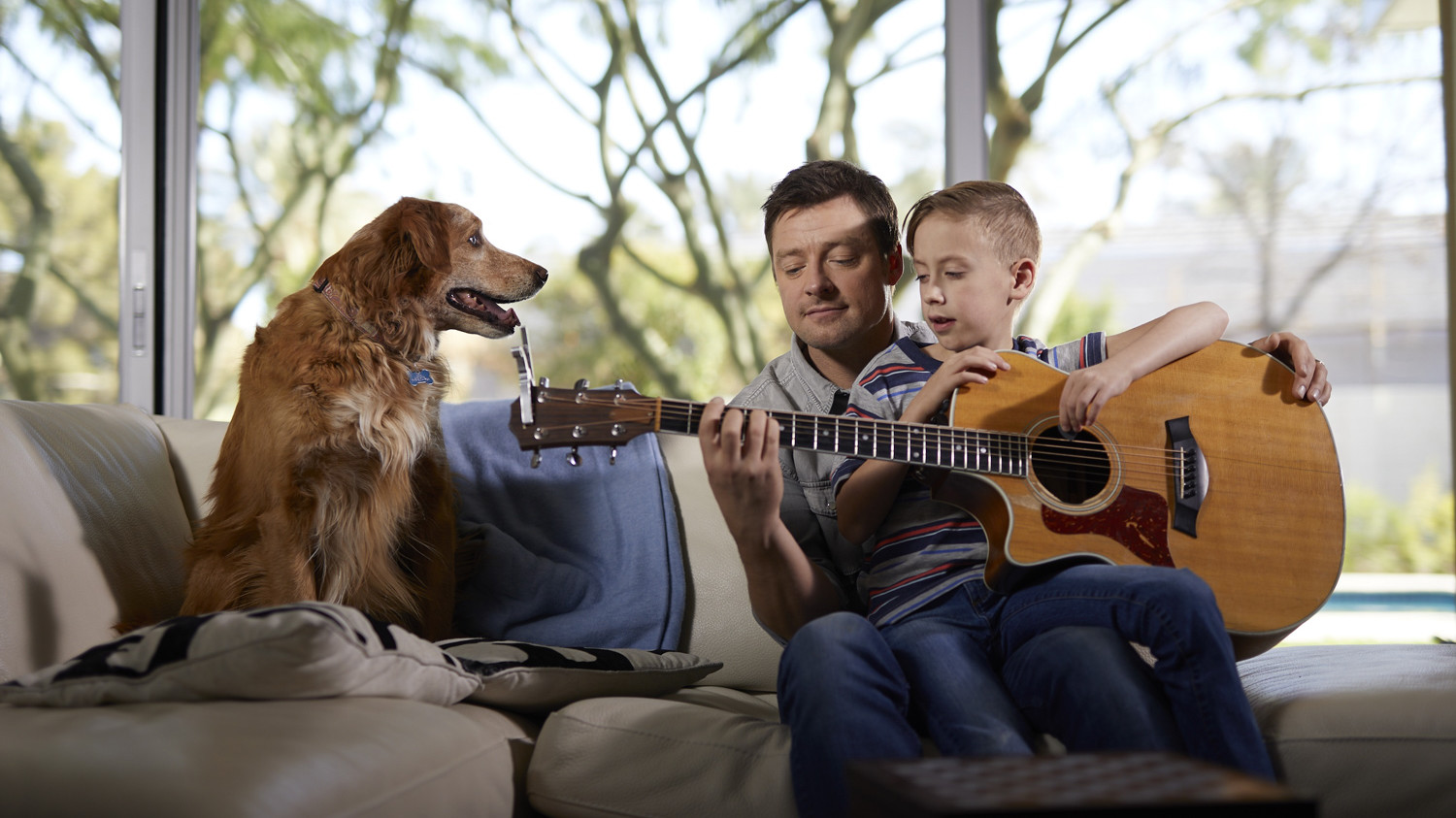 a man plays guitar with his son at home