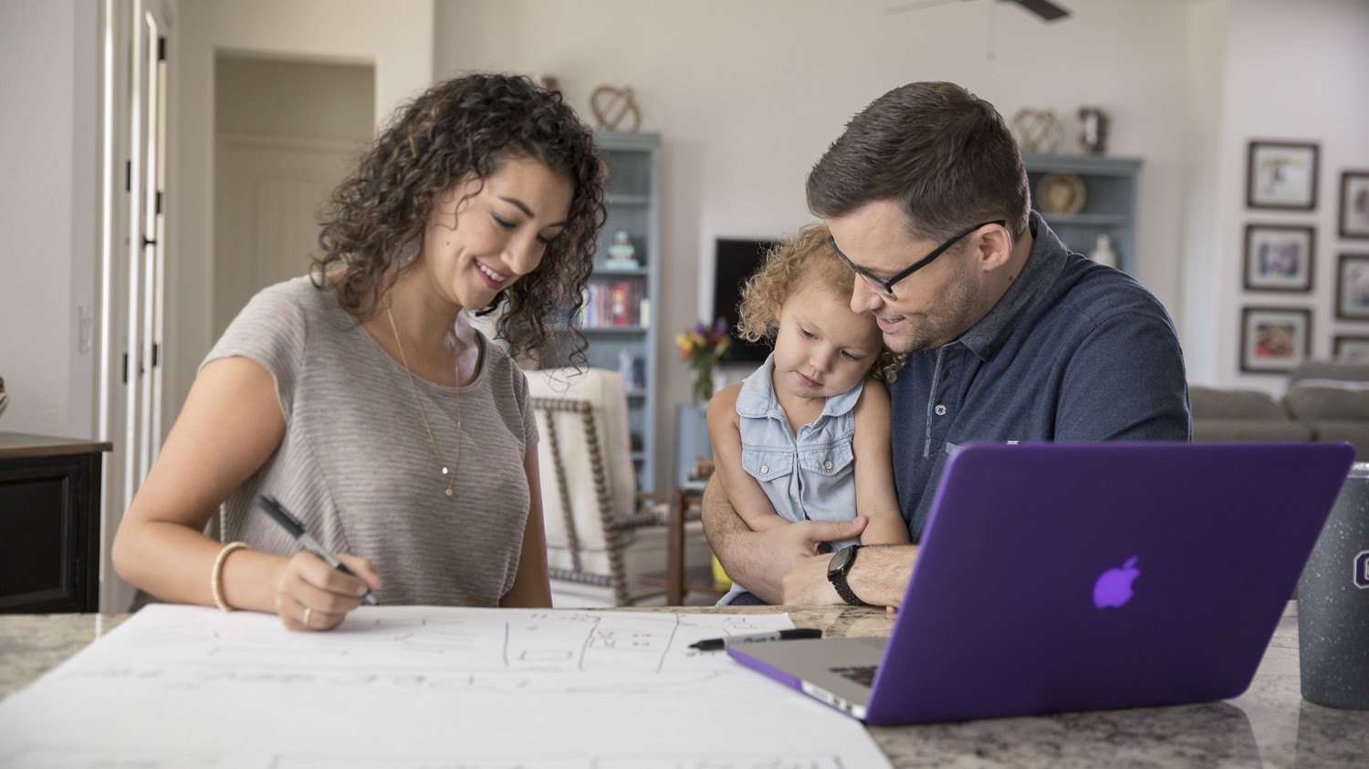 a husband and wife doing homework with their daughter