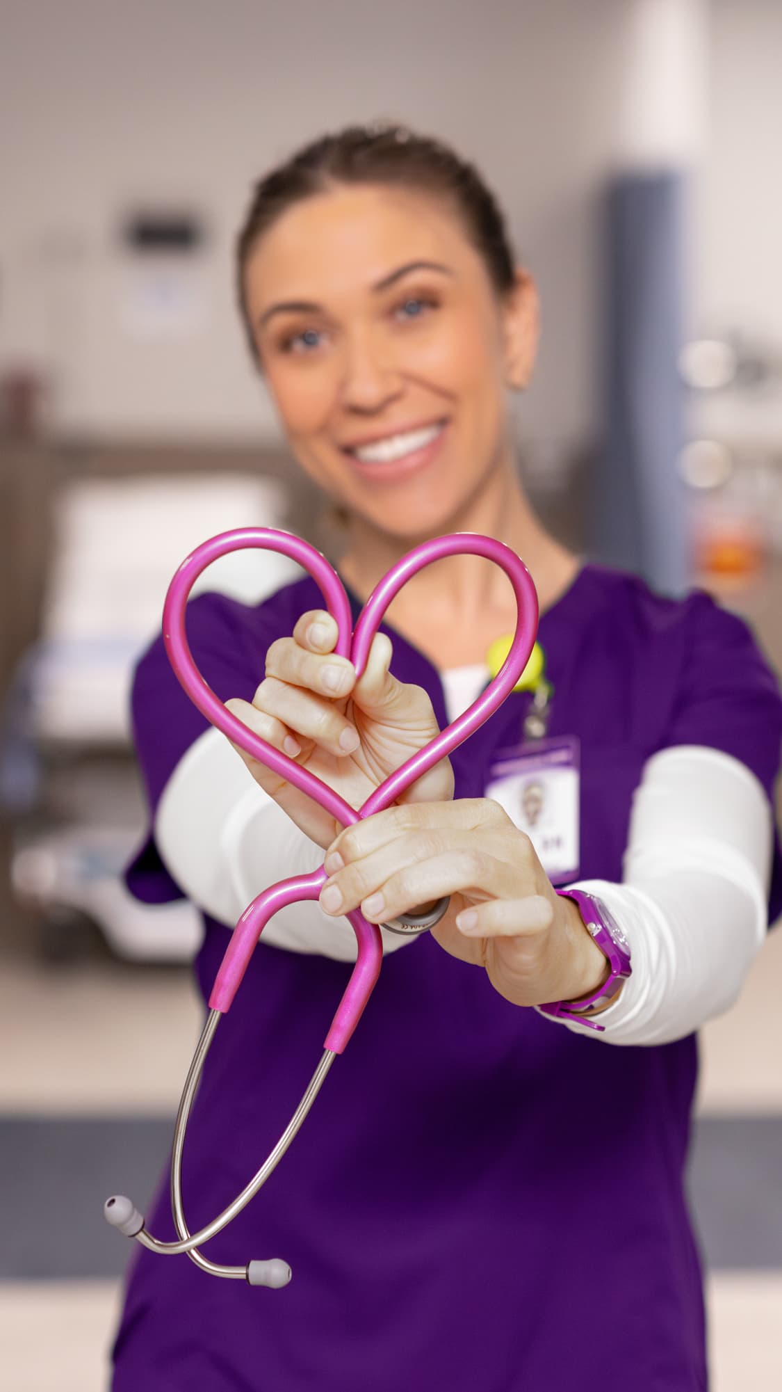 Female healthcare degree graduate smiling in hospital with stethoscope in heart shape