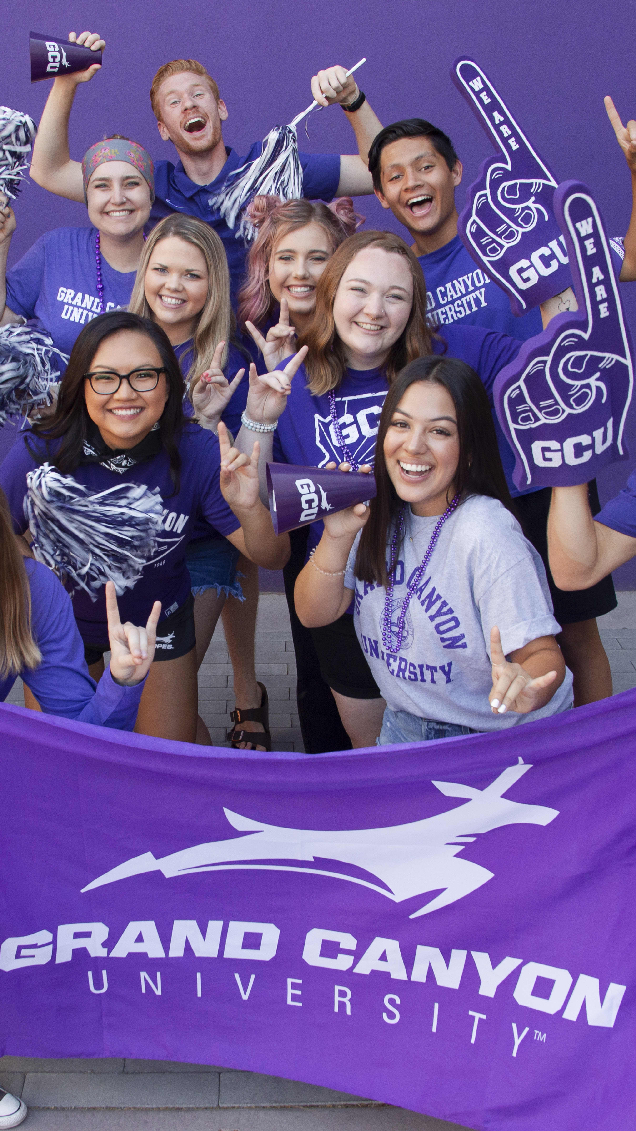 GCU students decked out in spirit gear waving a gcu flag