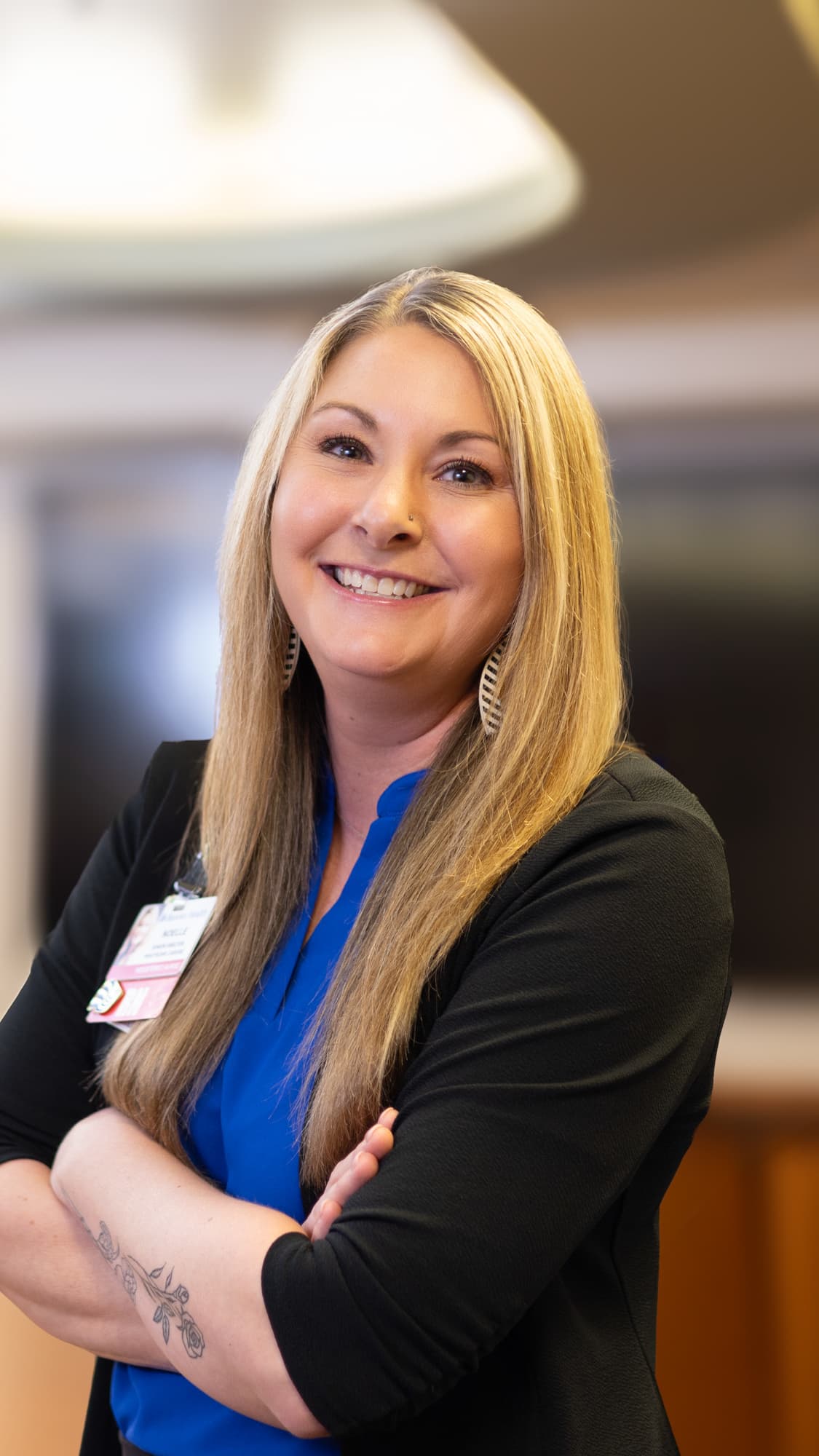 Healthcare professional standing in office setting smiling with her arms crossed
